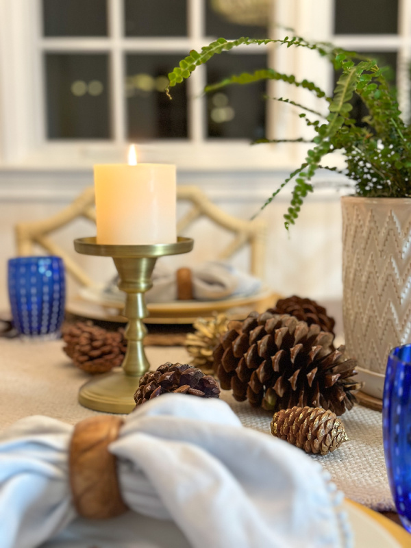 Holiday table setting with candles and pinecones.