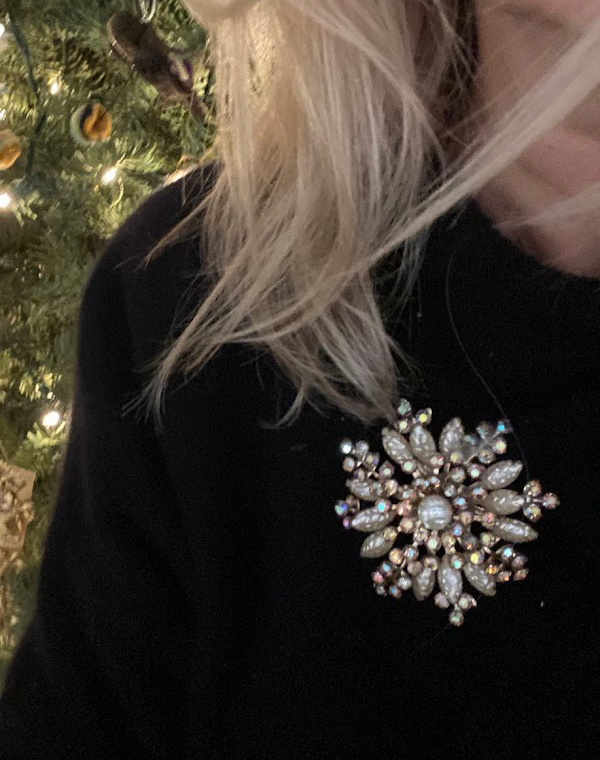 Close up of woman wearing snowflake brooch on coat lapel.