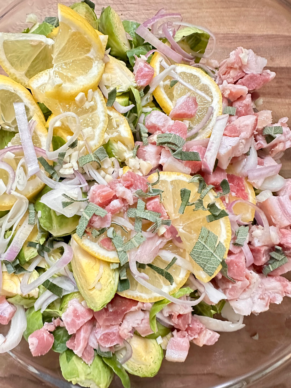 Bowl full Brussels sprouts, lemons, herbs and pancetta.