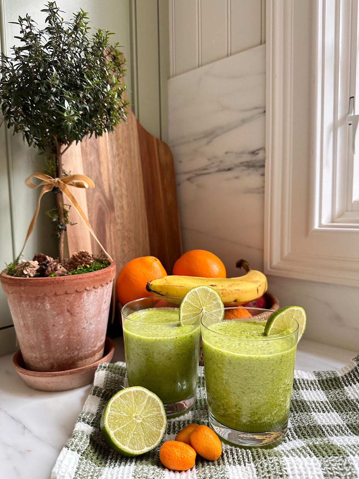 Two glasses of green juice on kitchen counter.
