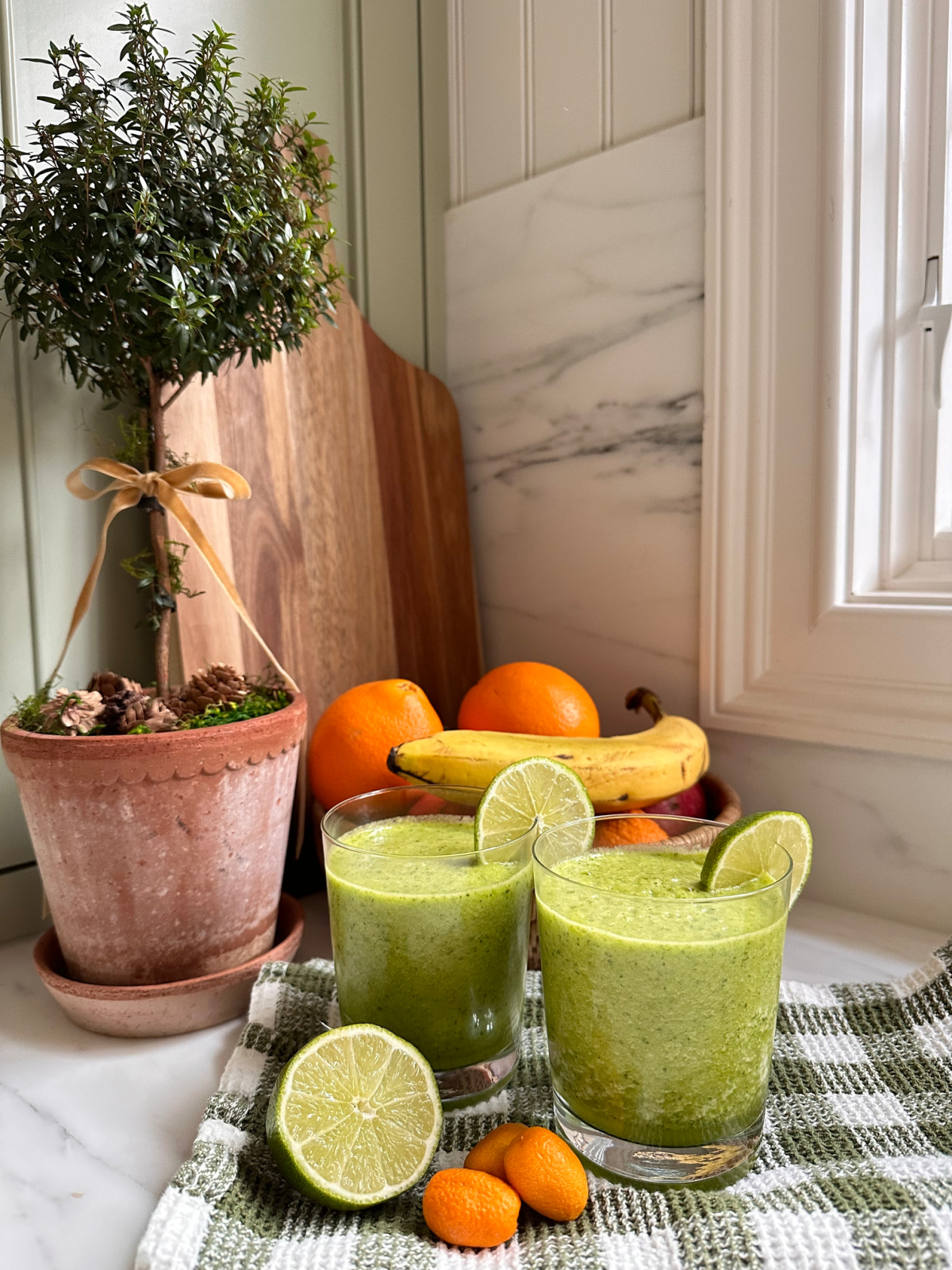Two glasses of green juice on kitchen counter.