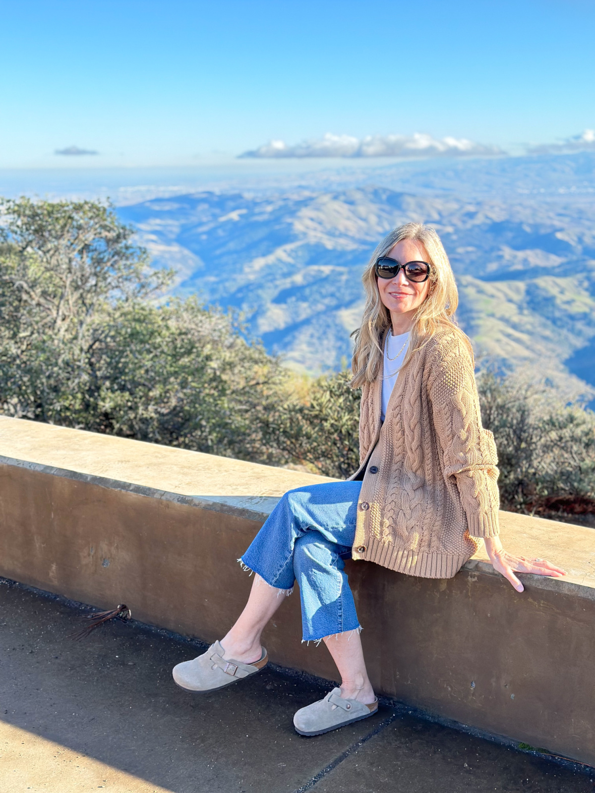 Woman seated on stone wall at peak of Mt. Diablo.