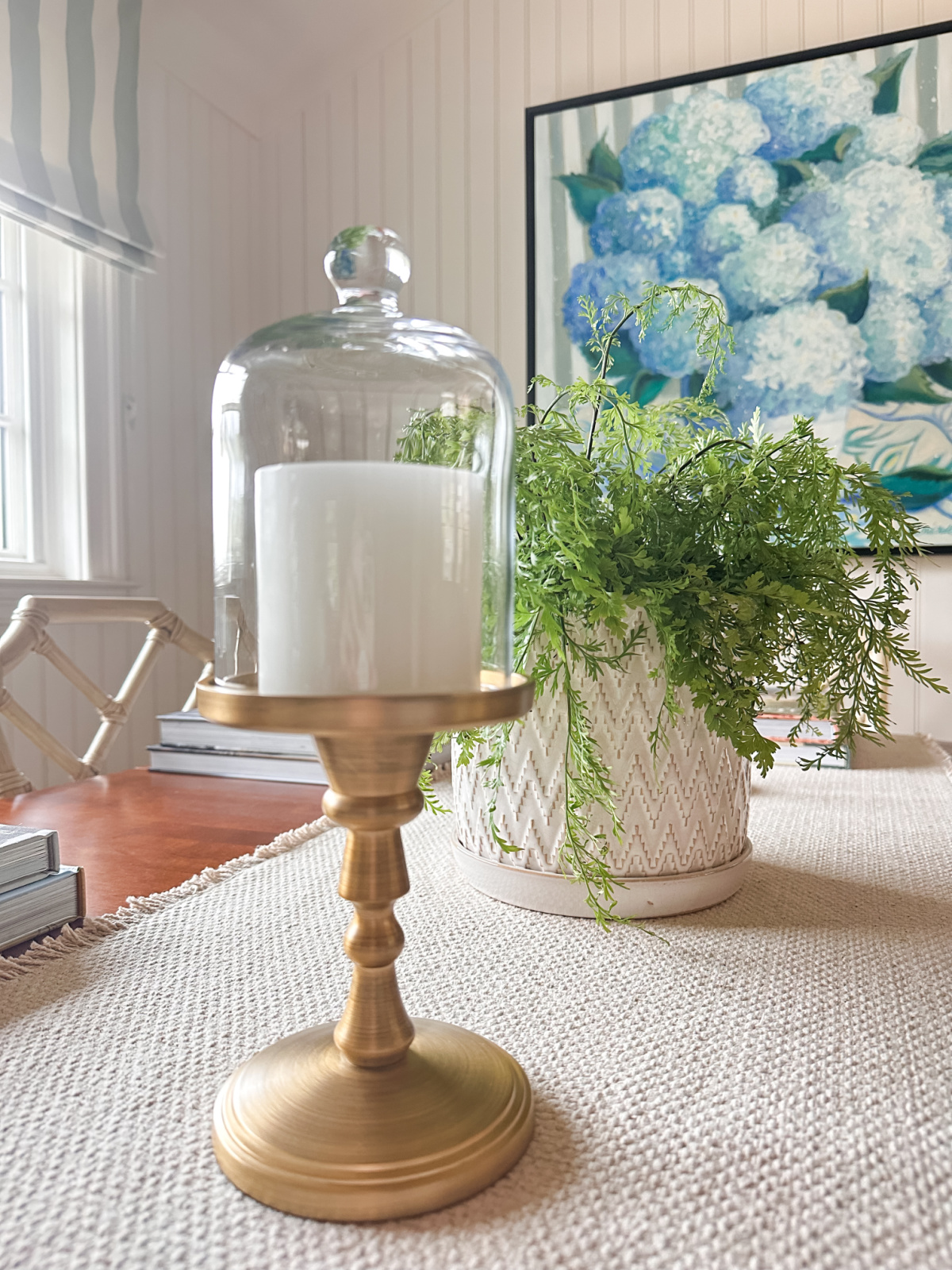 Candleholder on dining table covered by glass cloche.