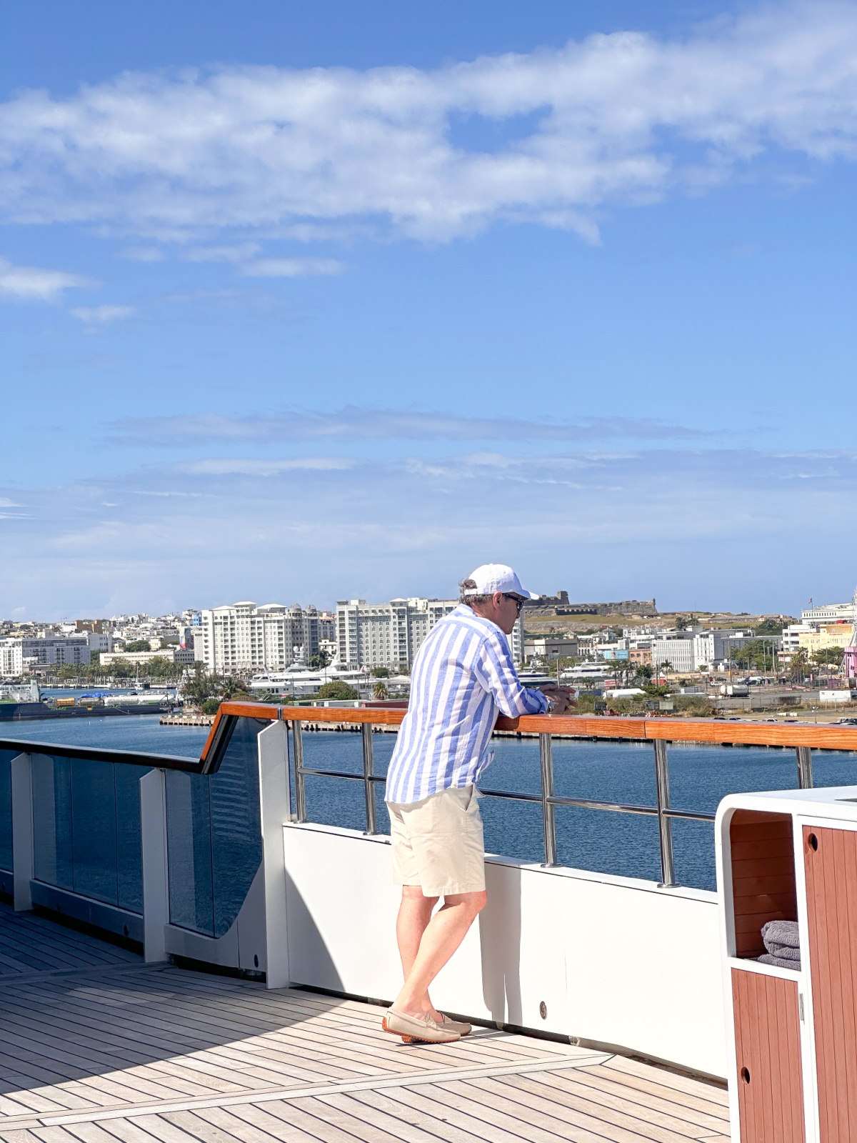 Man in striped shirt looking out from deck of Evrima yacht.