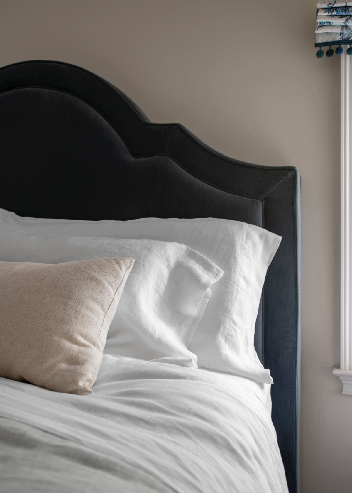 Pillows with linen cases against blue velvet headboard.