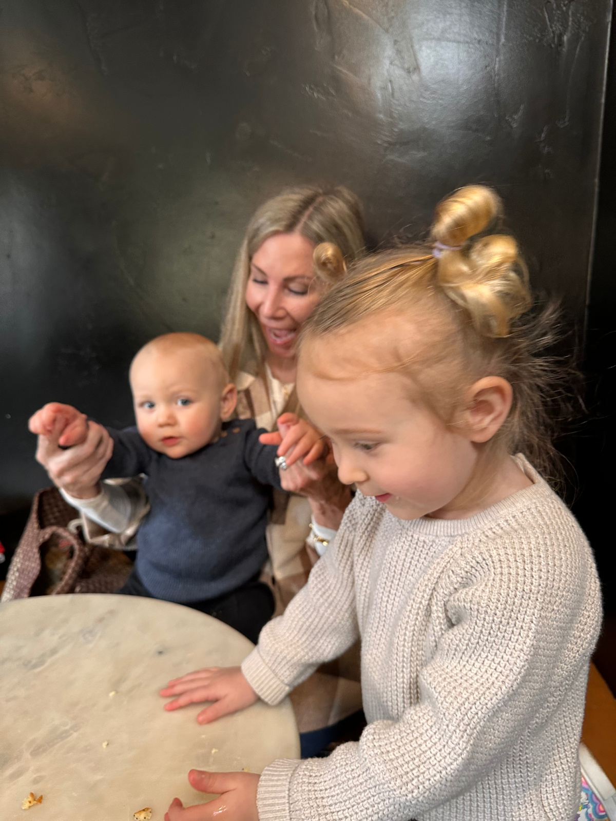 Woman sitting with two littles at coffee shop.