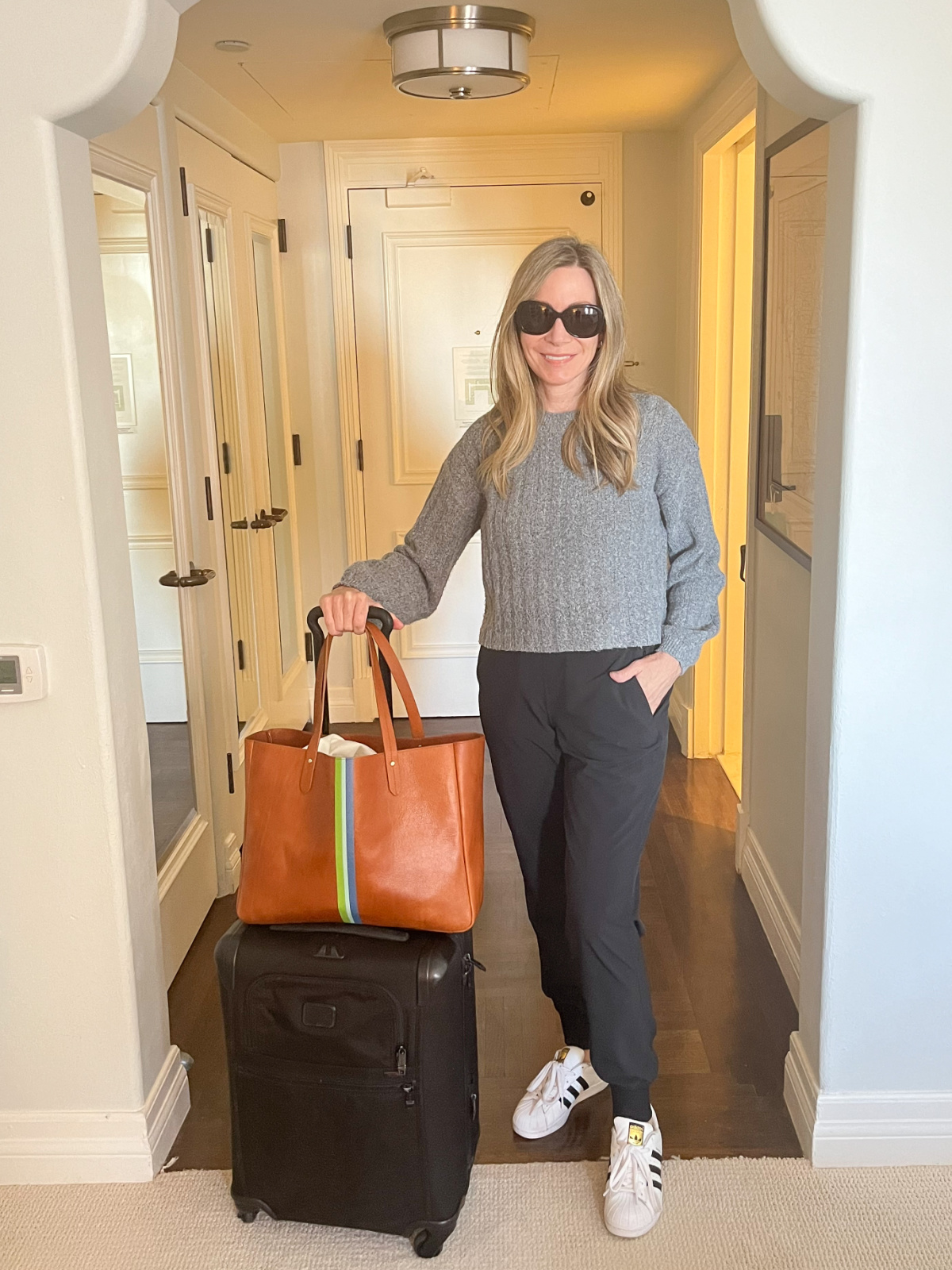 Woman standing next to luggage in hotel lobby.