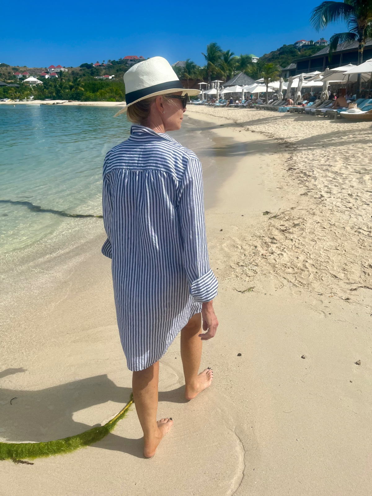 Woman wearing shirt dress beach cover up walking on beach at St. Barths.