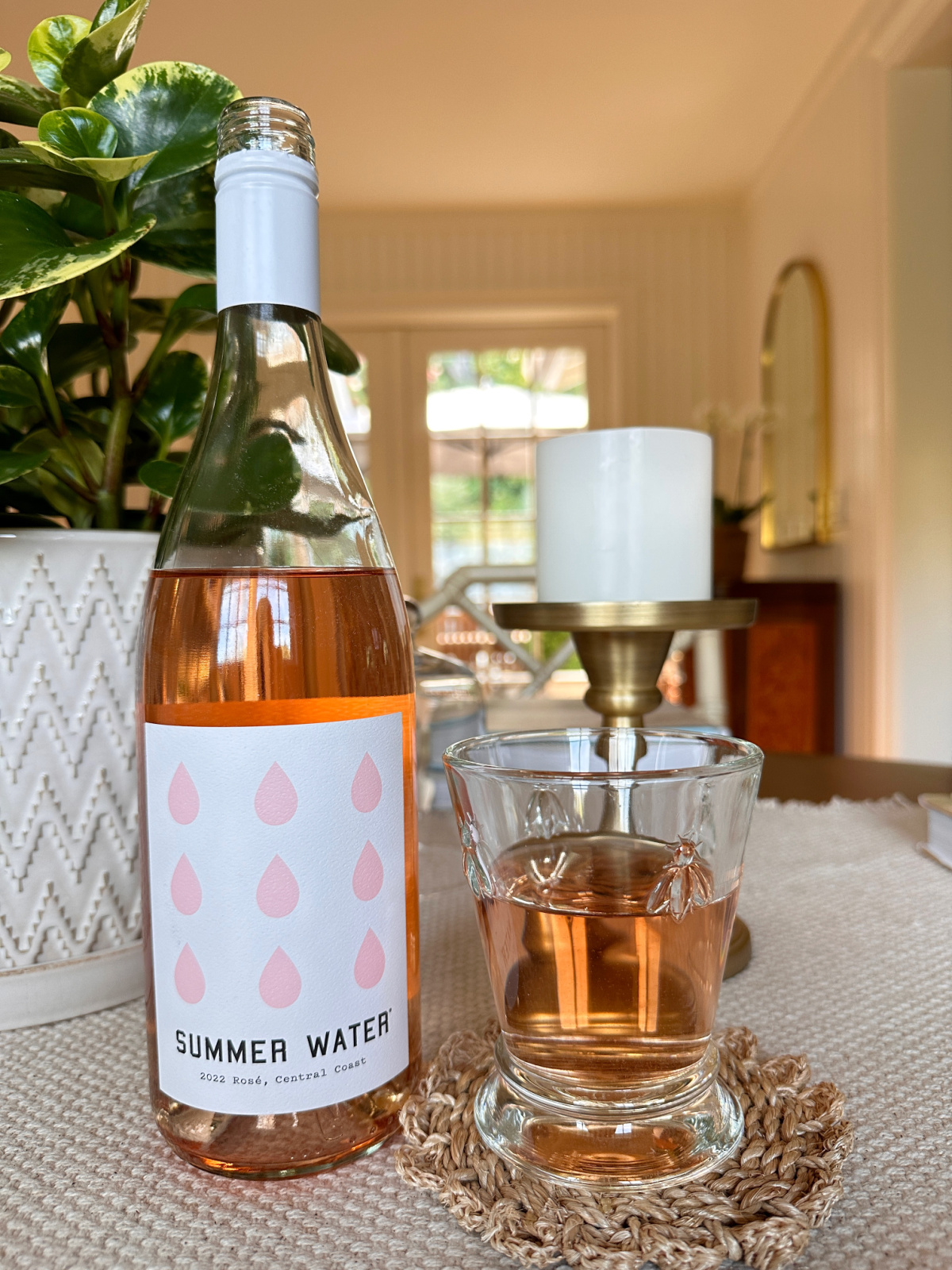 Bottle of Summer Water next to wine glass on dining table.