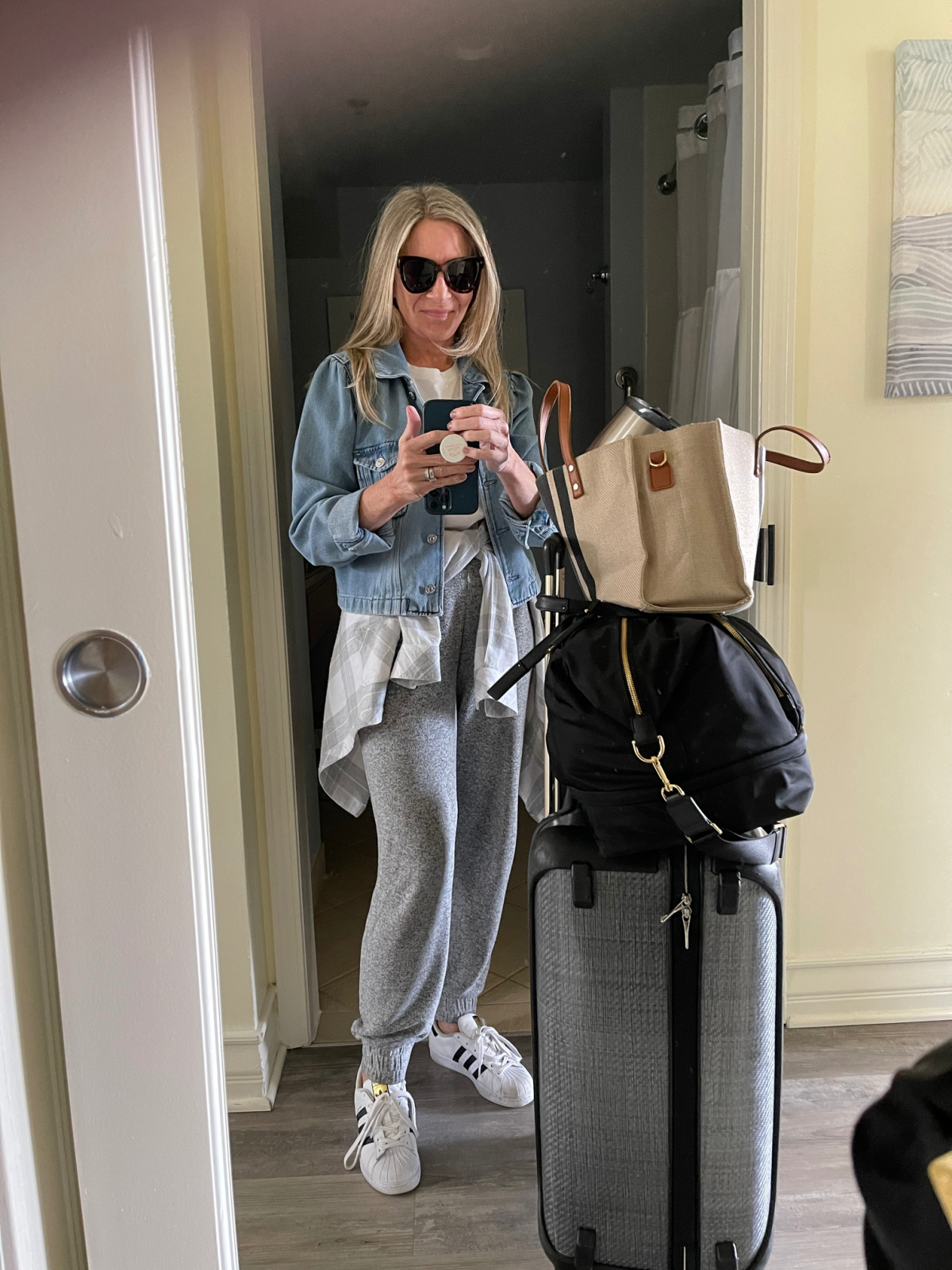 Woman taking selfie standing next to luggage.
