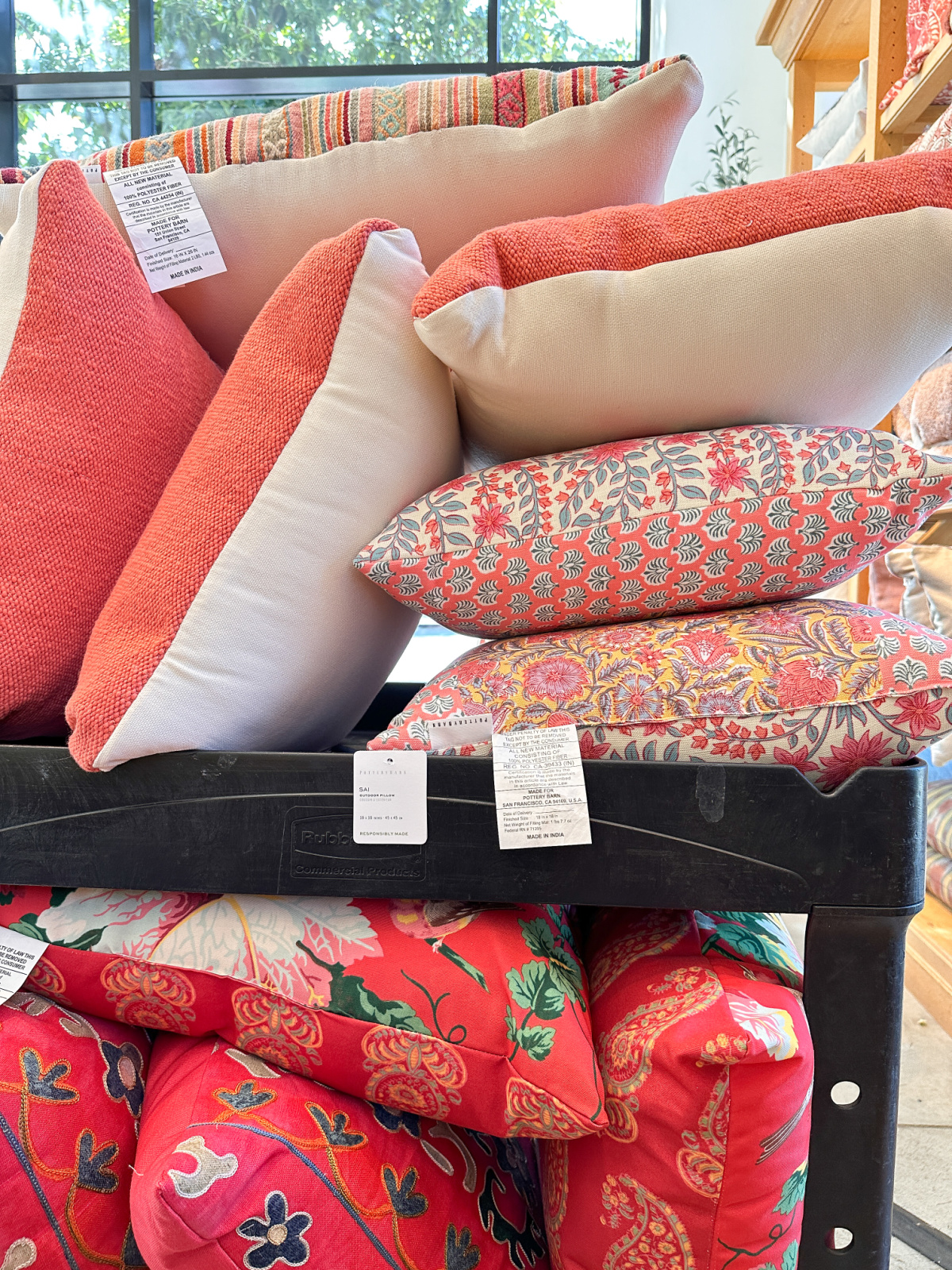 Coral and floral outdoor pillows on rack at Pottery Barn.