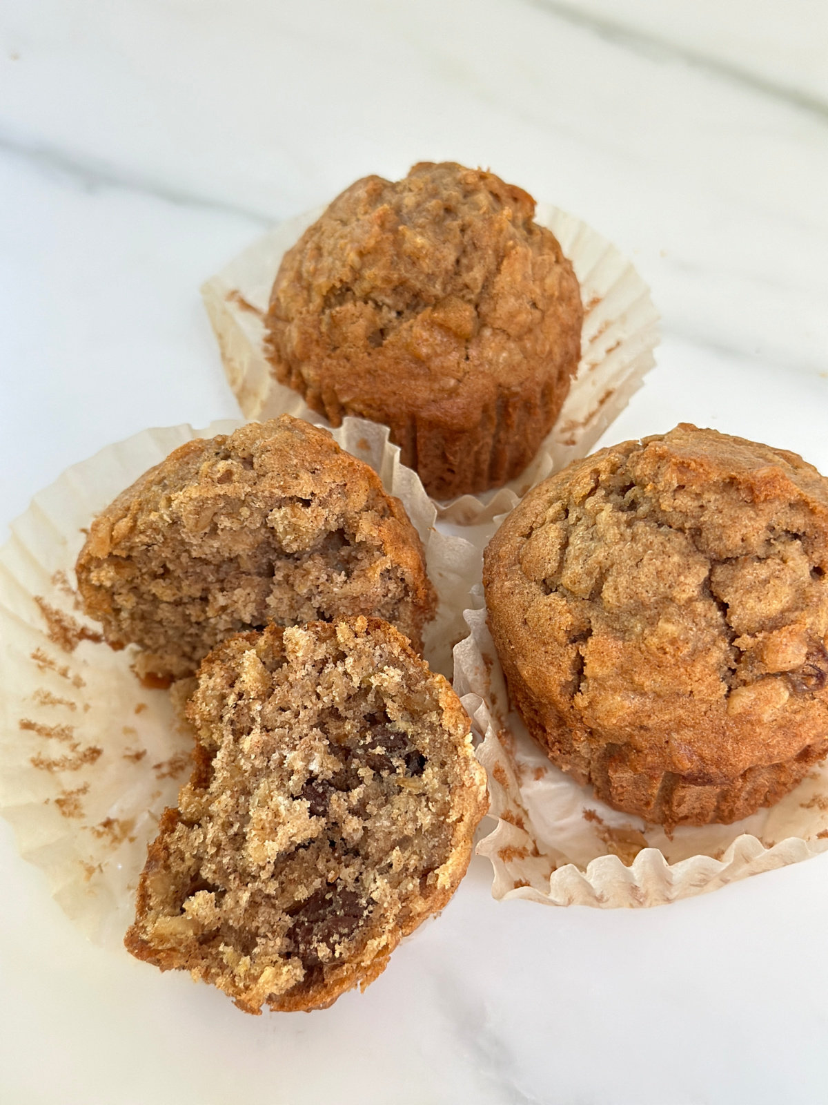 Three oatmeal muffins on countertop.