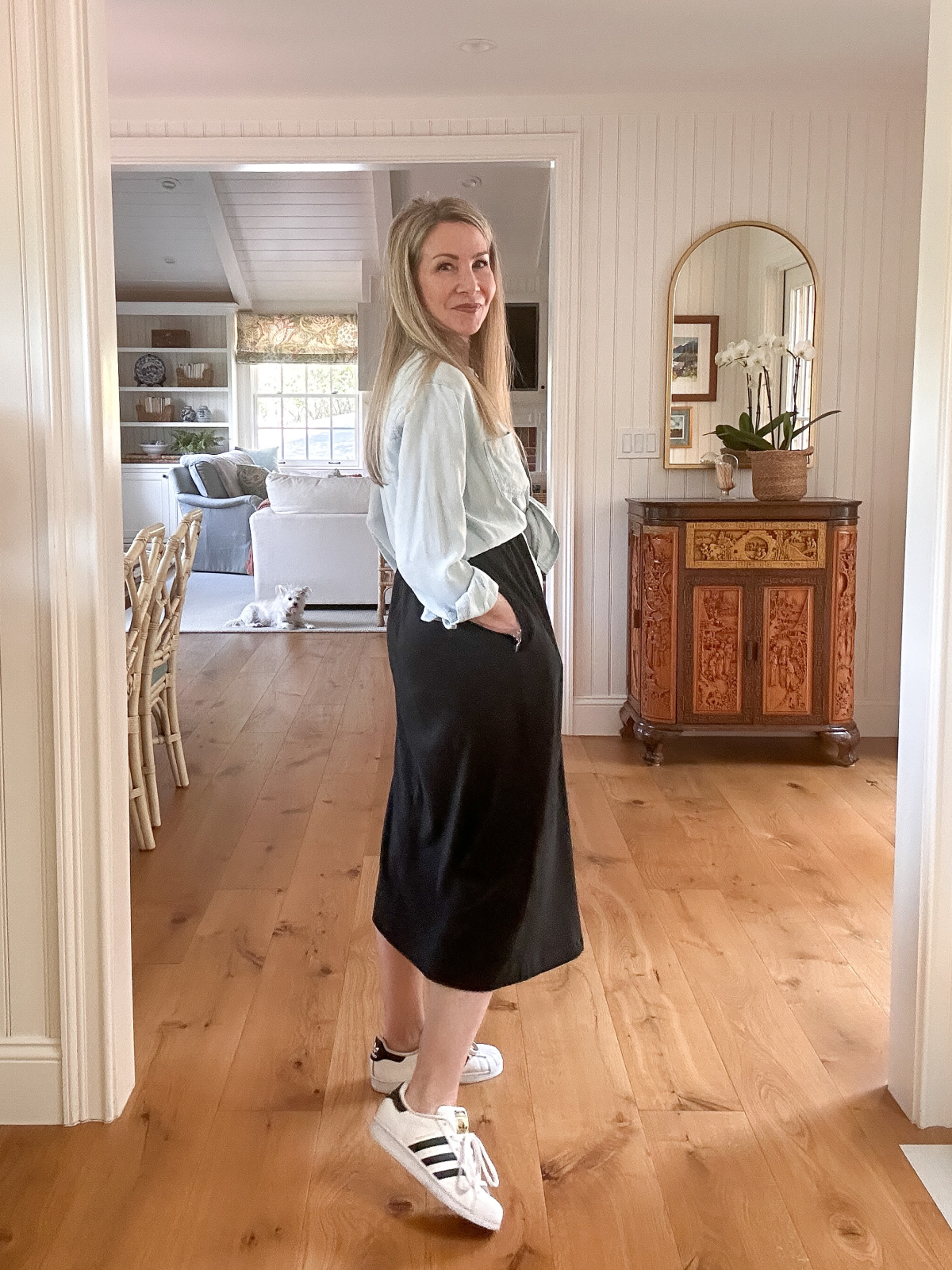 Woman wearing black dress, chambray shirt and Adidas Superstars.