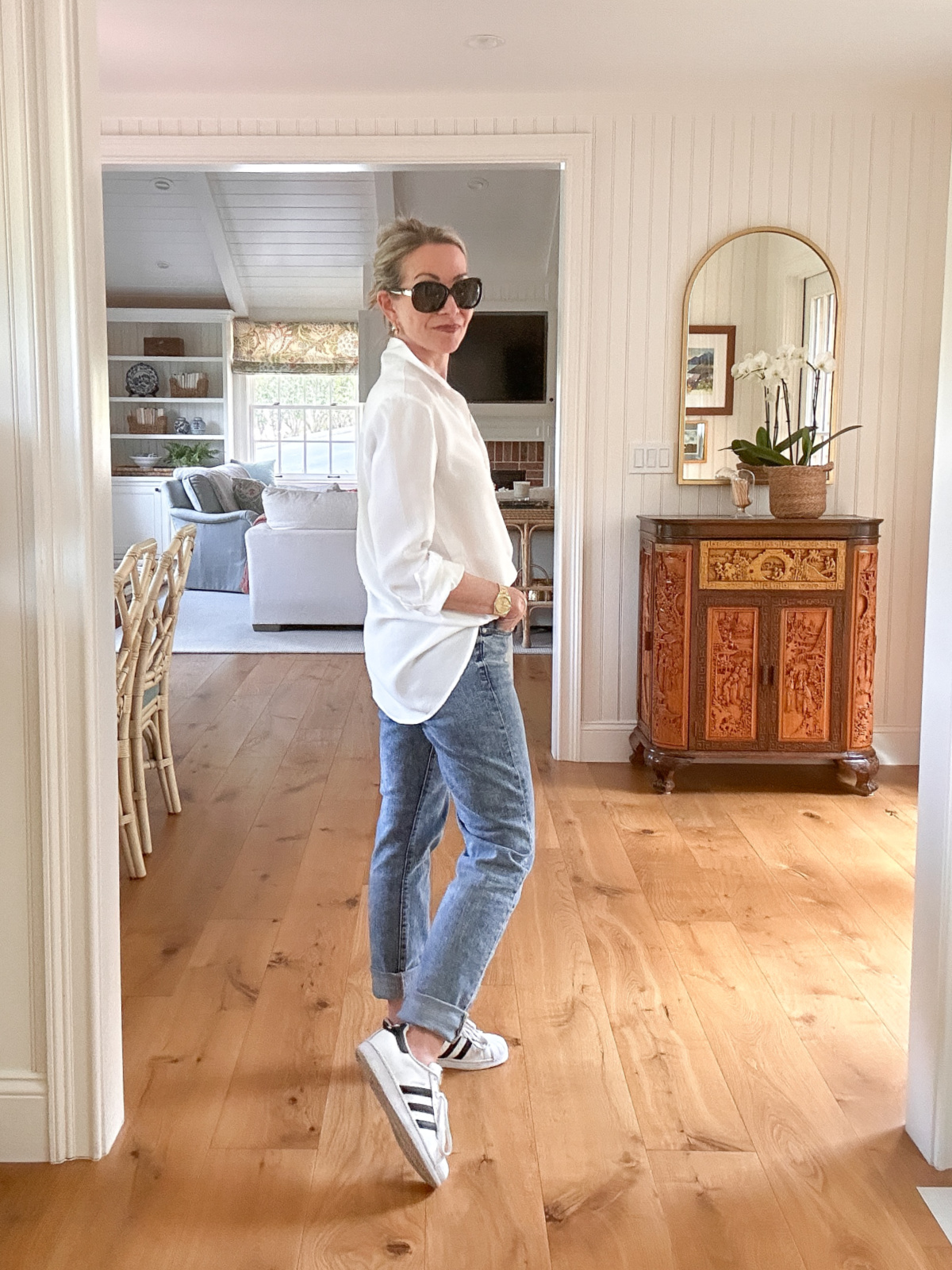 Woman wearing white shirt and jeans with Adidas Superstars.