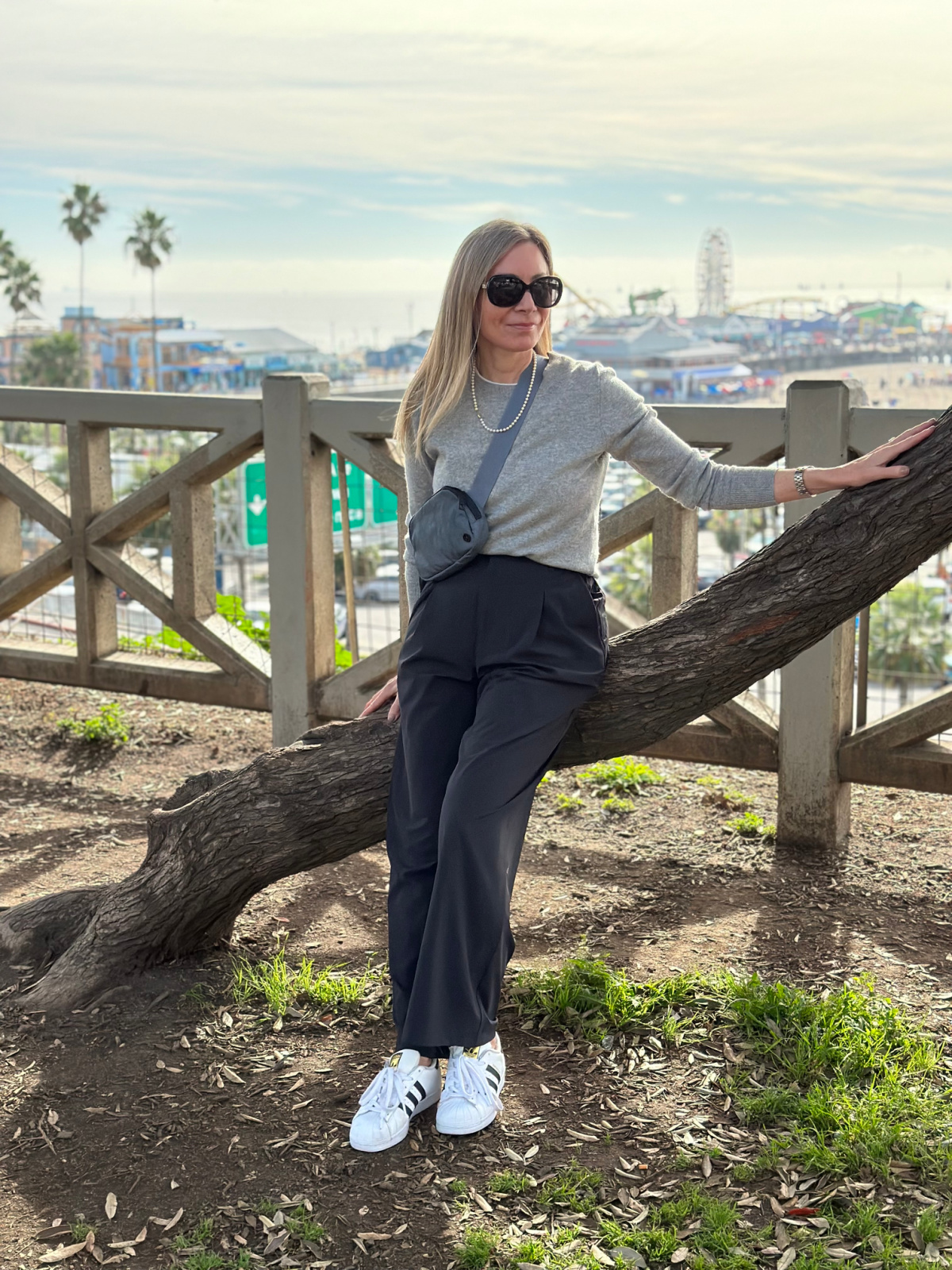 Woman leaning against tree overlooking Santa Monica Pier.