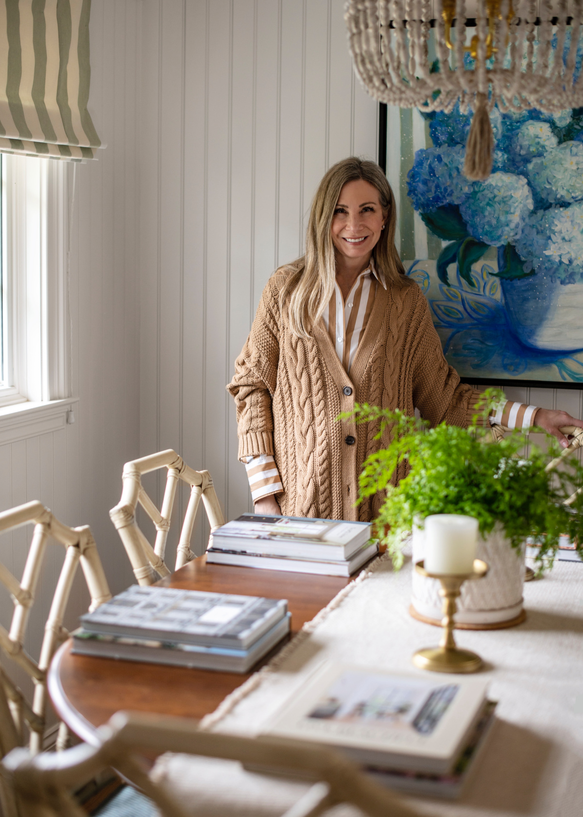 Woman standing behind casual dining table set with books.