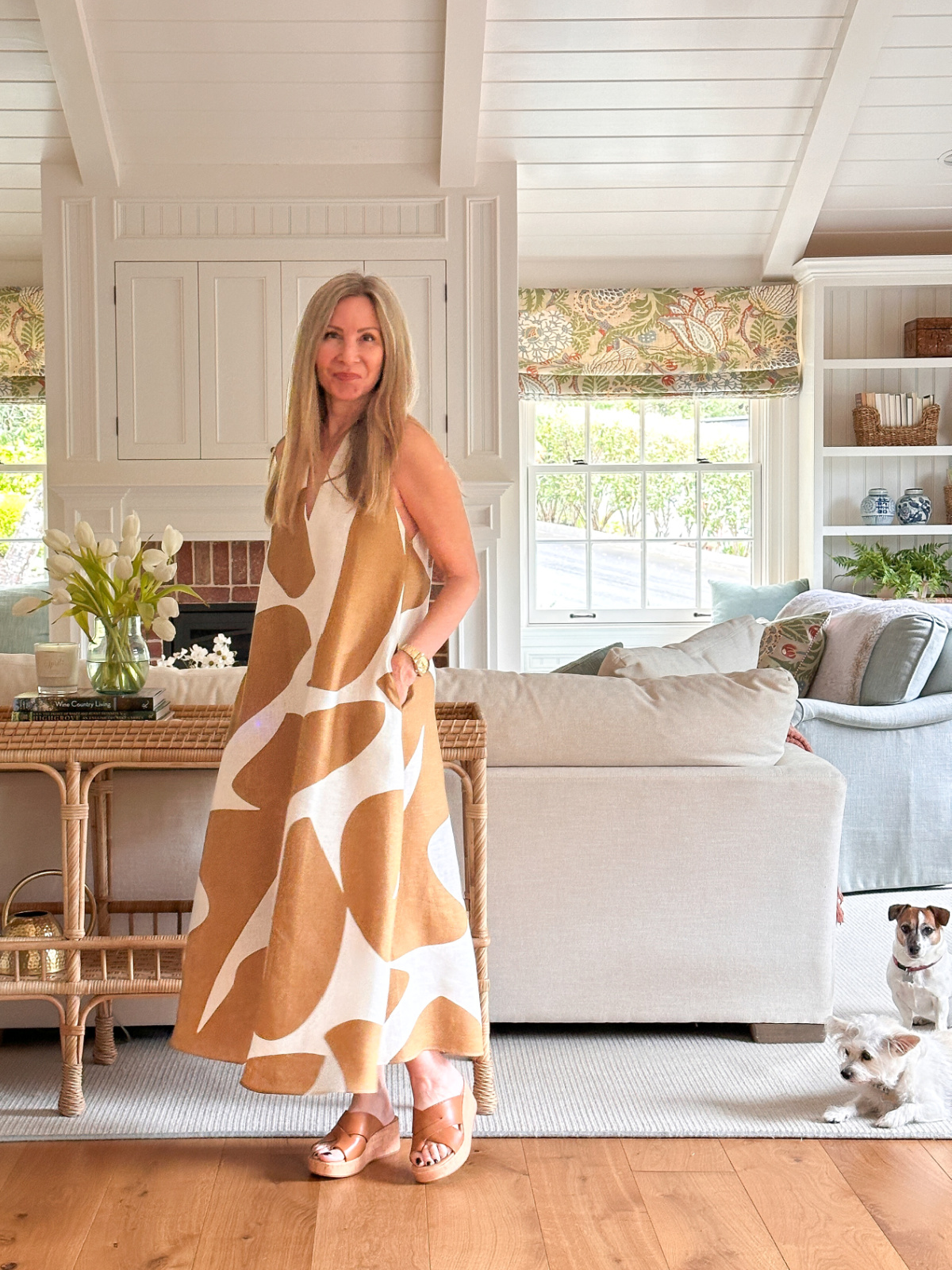 Woman wearing giraffe print linen dress from banana republic with two little dogs sitting on floor beside her.