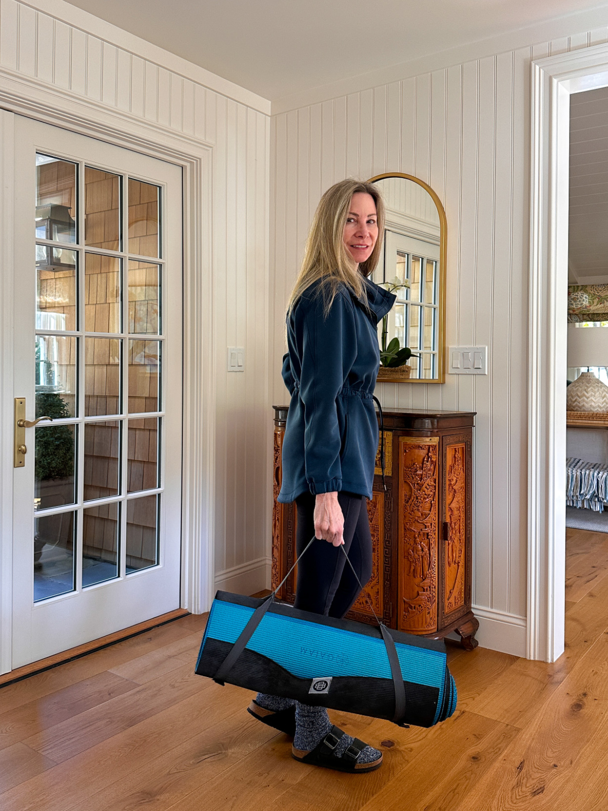 Woman dressed for yoga, holding yoga mat.