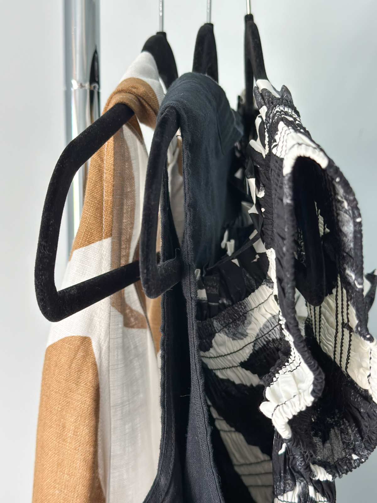 Three dresses hanging on rack.