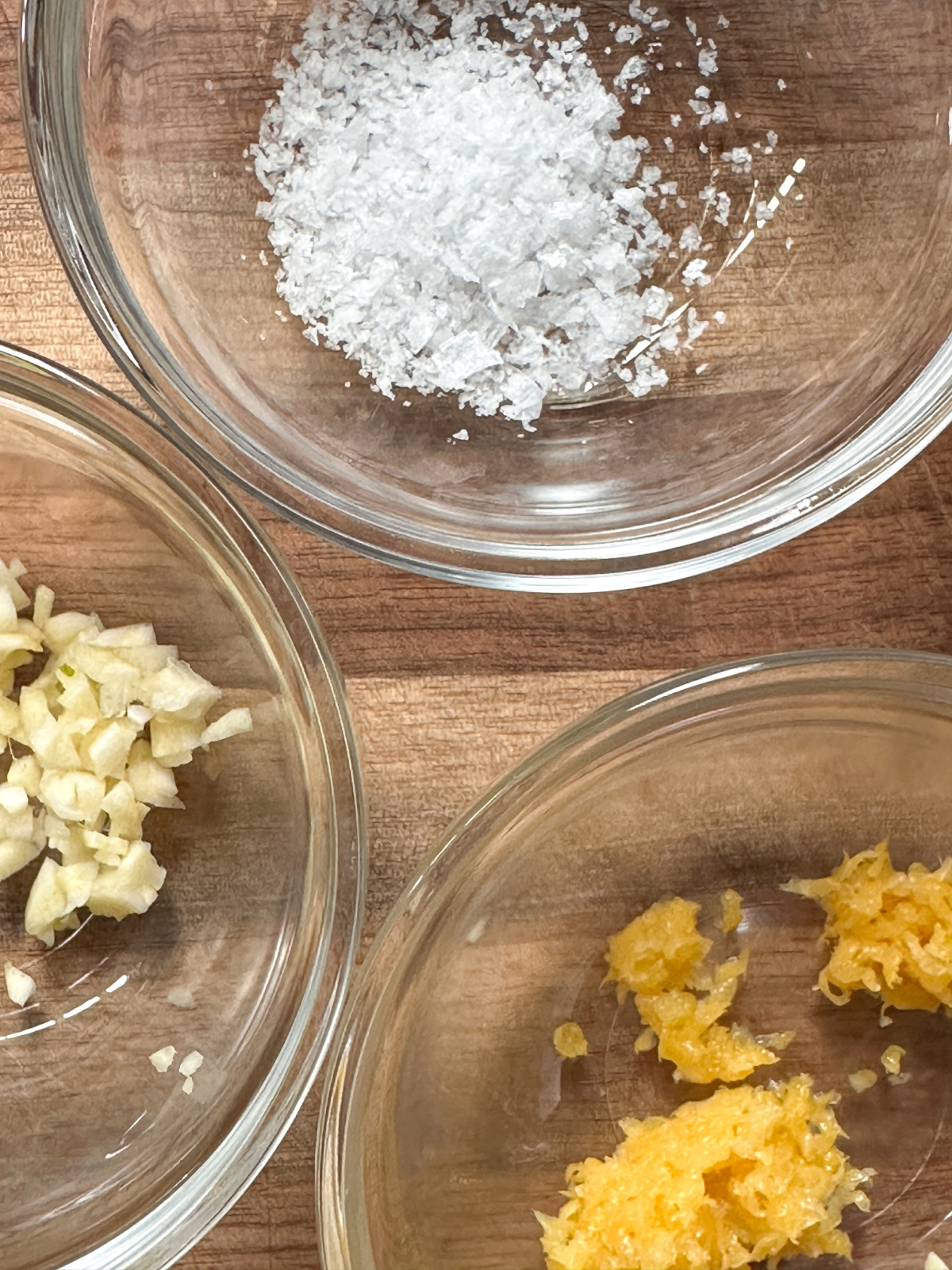 Small dishes of minced garlic, sea salt, and lemon zest.