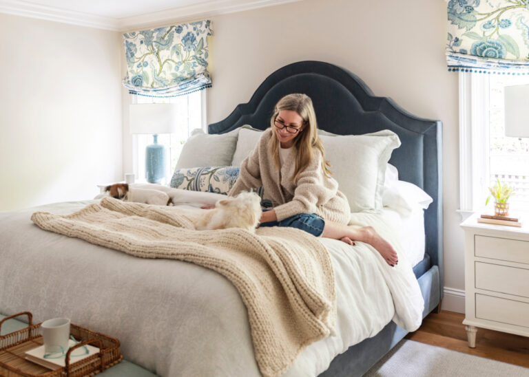 Woman sitting on bed with little Jack Russell Terrier.