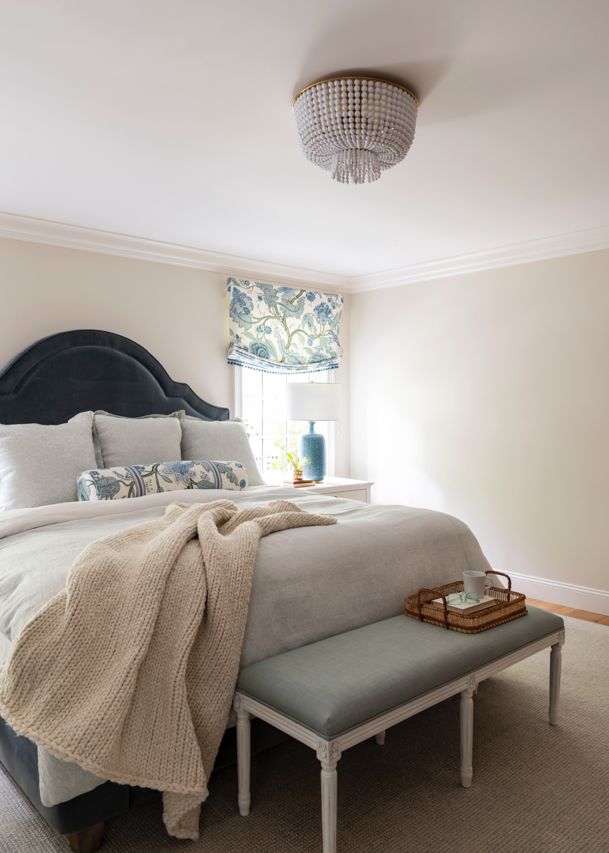 Tranquil bedroom with blue velvet headboard, linen bedding and end of bed bench.