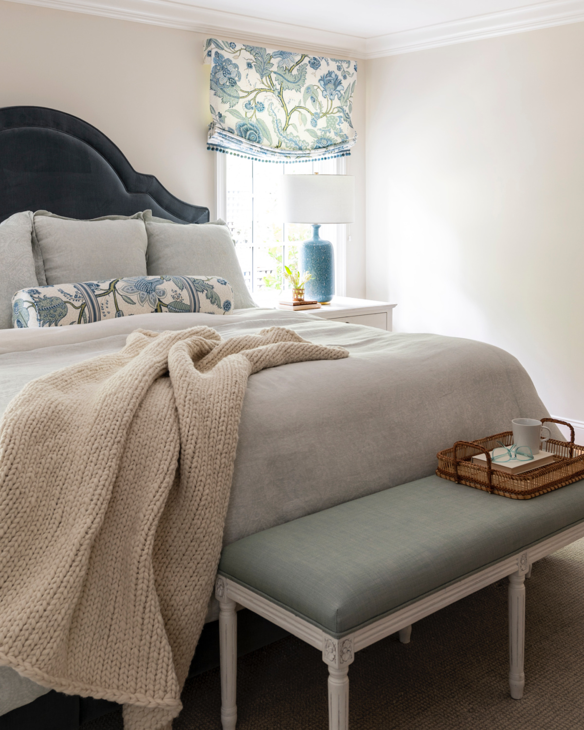 Tranquil bedroom with blue velvet headboard, linen bedding and end of bed bench.