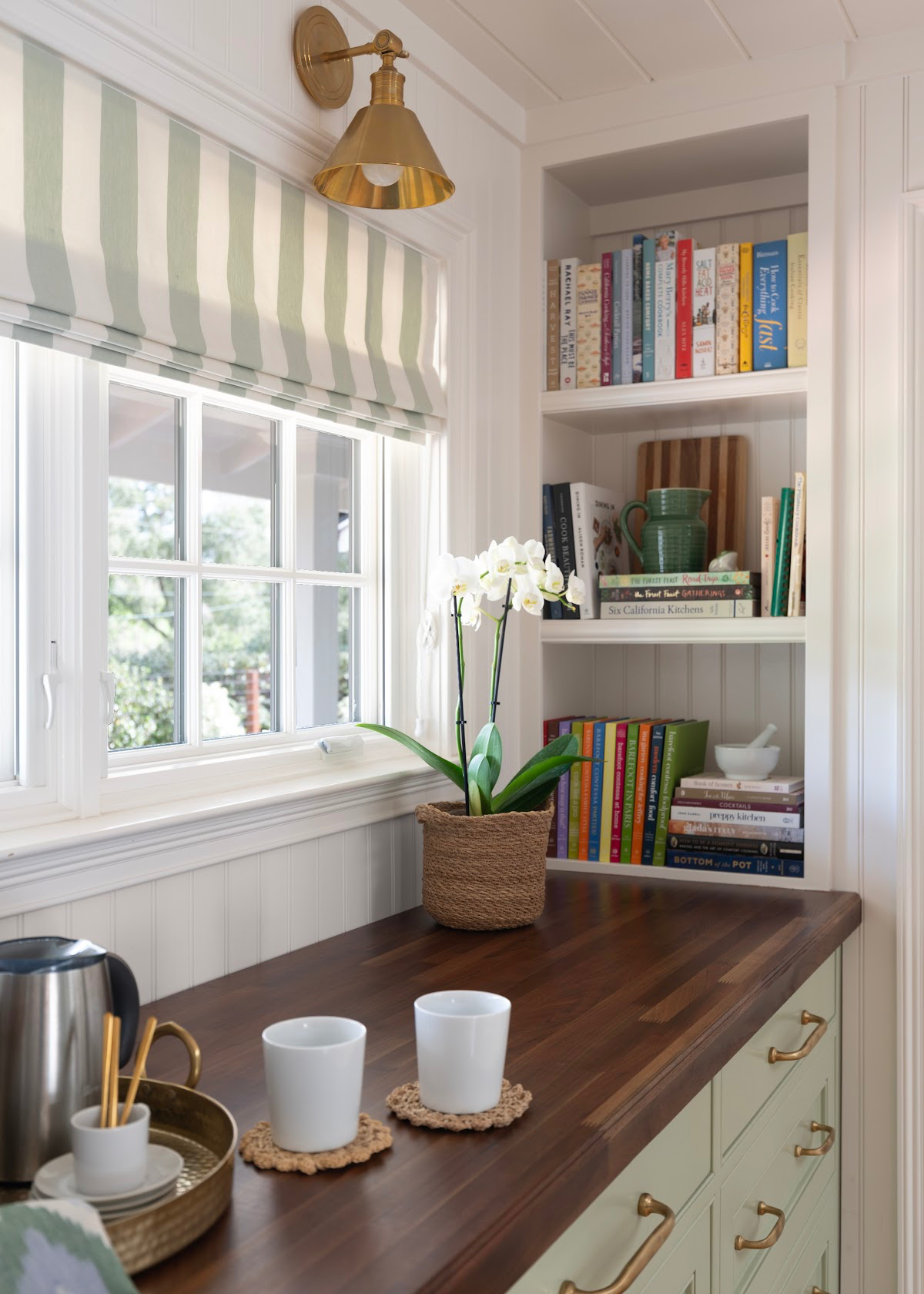 Milk frother and white mugs on kitchen buffet.