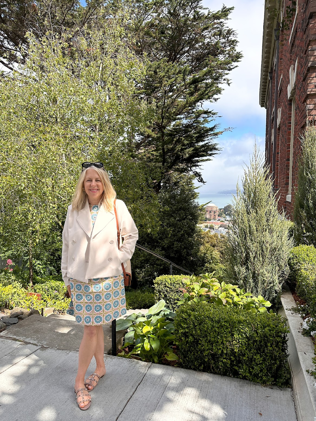 Woman wearing shift dress and jacket on street overlooking the Palace of Fine Arts.