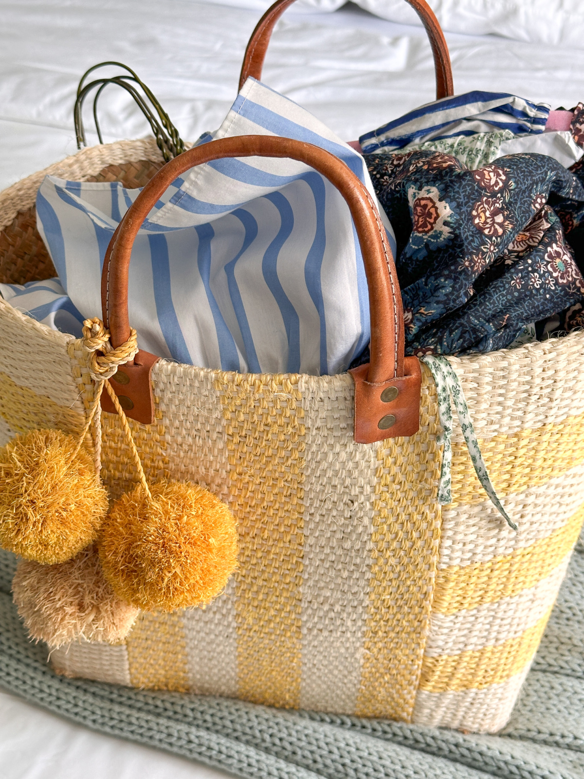 Yellow and white striped tote filled with summer dresses.