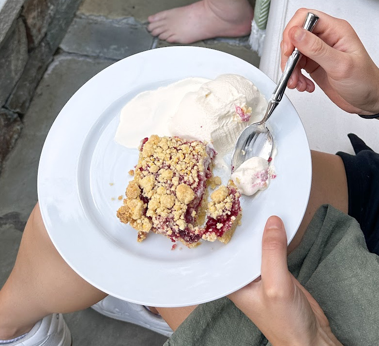 Slice of raspberry Cornmeal crumble ton plate with vanilla ice cream.