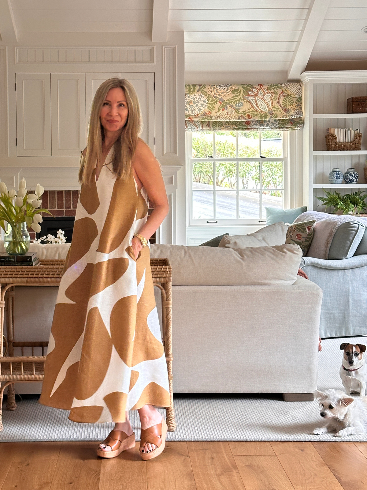 Woman wearing Banana Republic dress and Born sandals in living room with two small dogs.