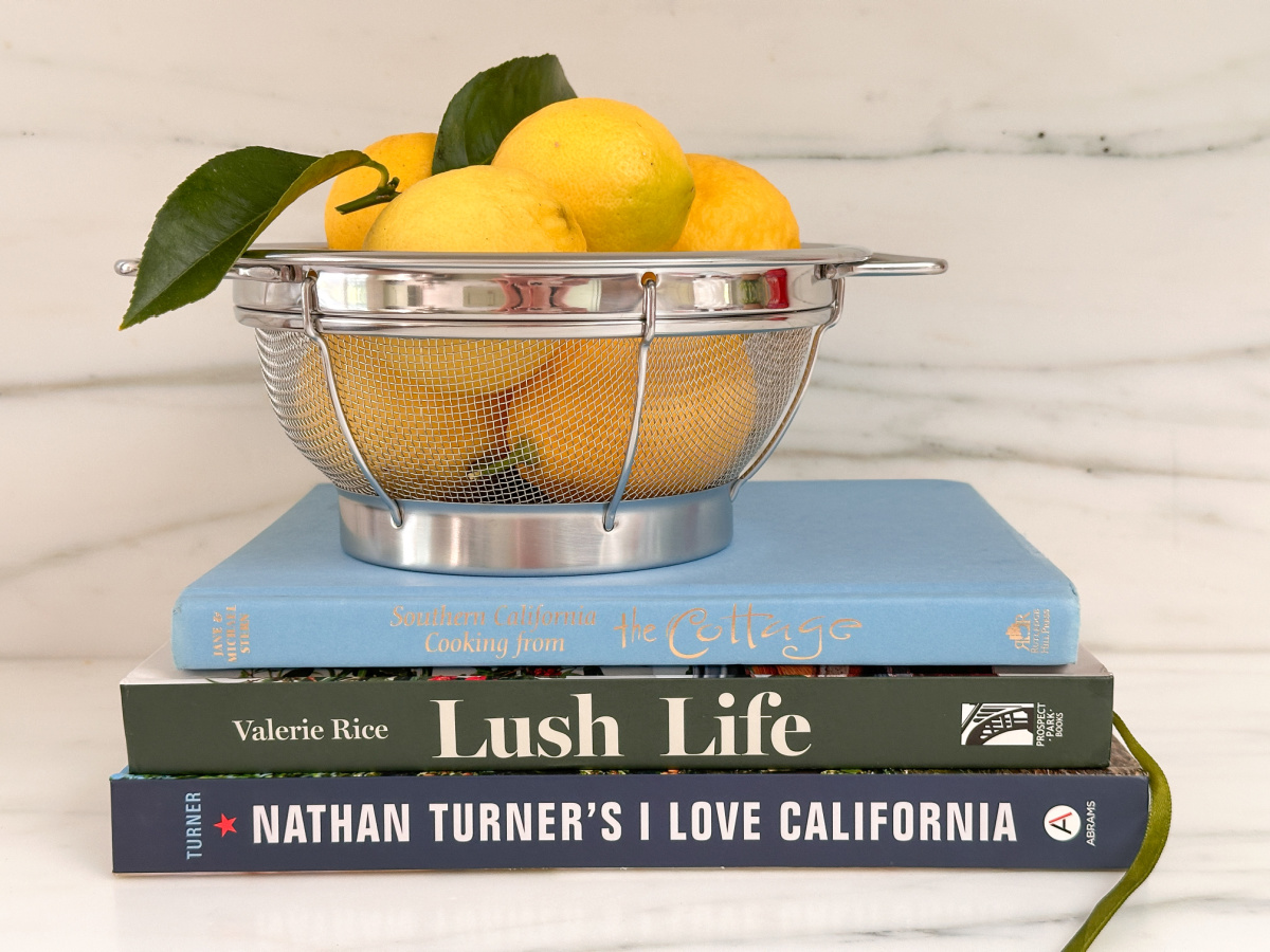 Collander full of lemons sitting on three books on kitchen counter.