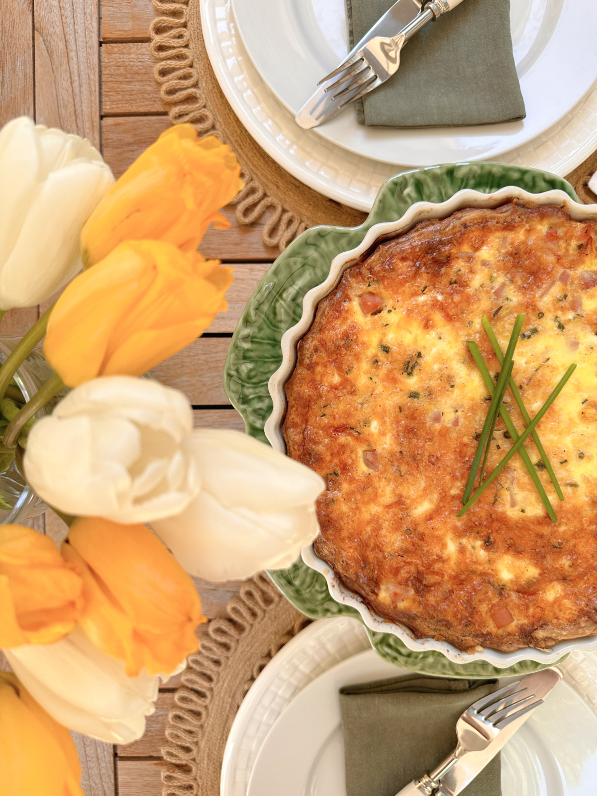 Overhead shot of table set for Mother's Day brunch with yellow and white tulips and a quiche.