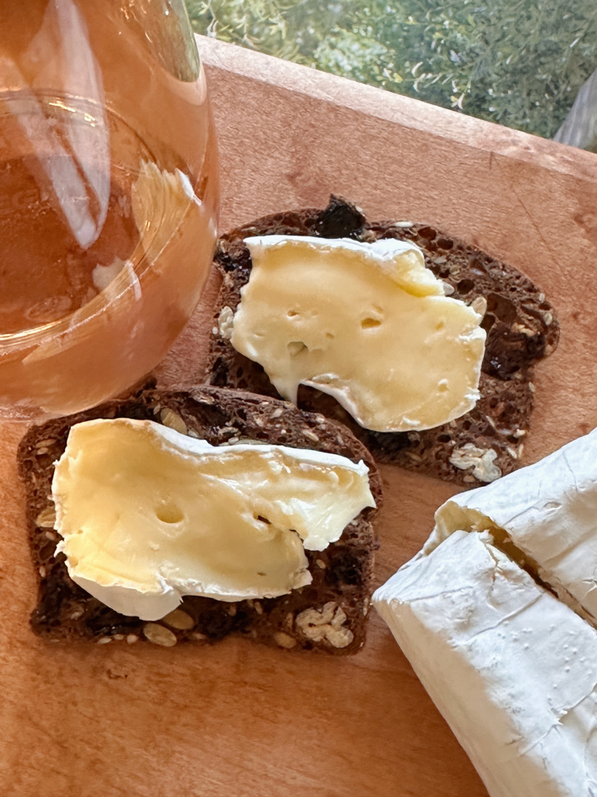 Wood board with cracker and cheese and glass of rose.