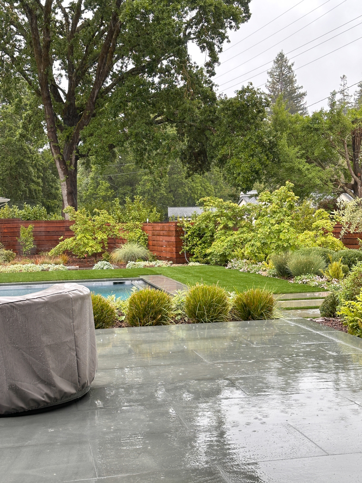 Outdoor pool and grass area in the rain.