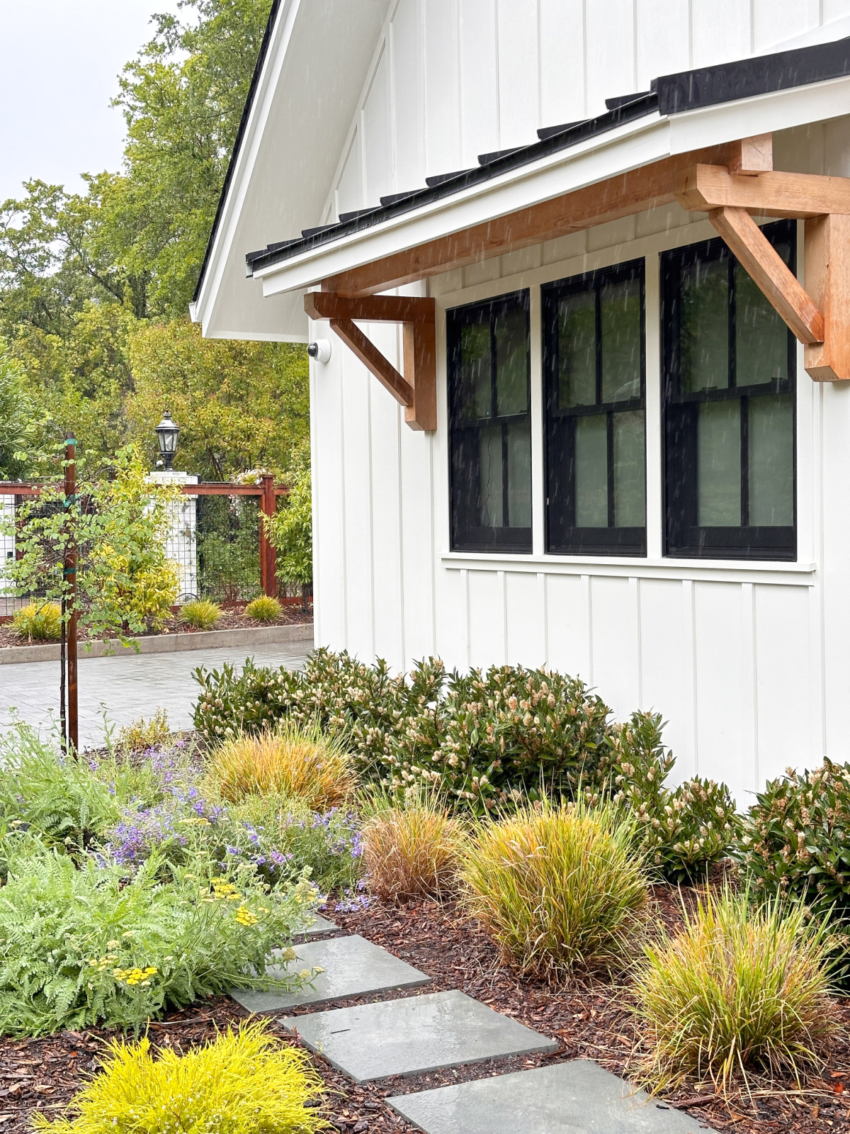 Exterior of white modern farm house and side garden.