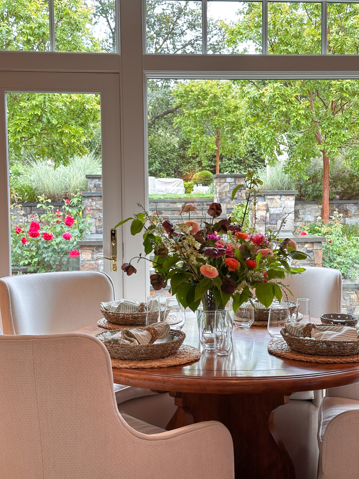 Round table set with florals looking out over beautiful gardens.