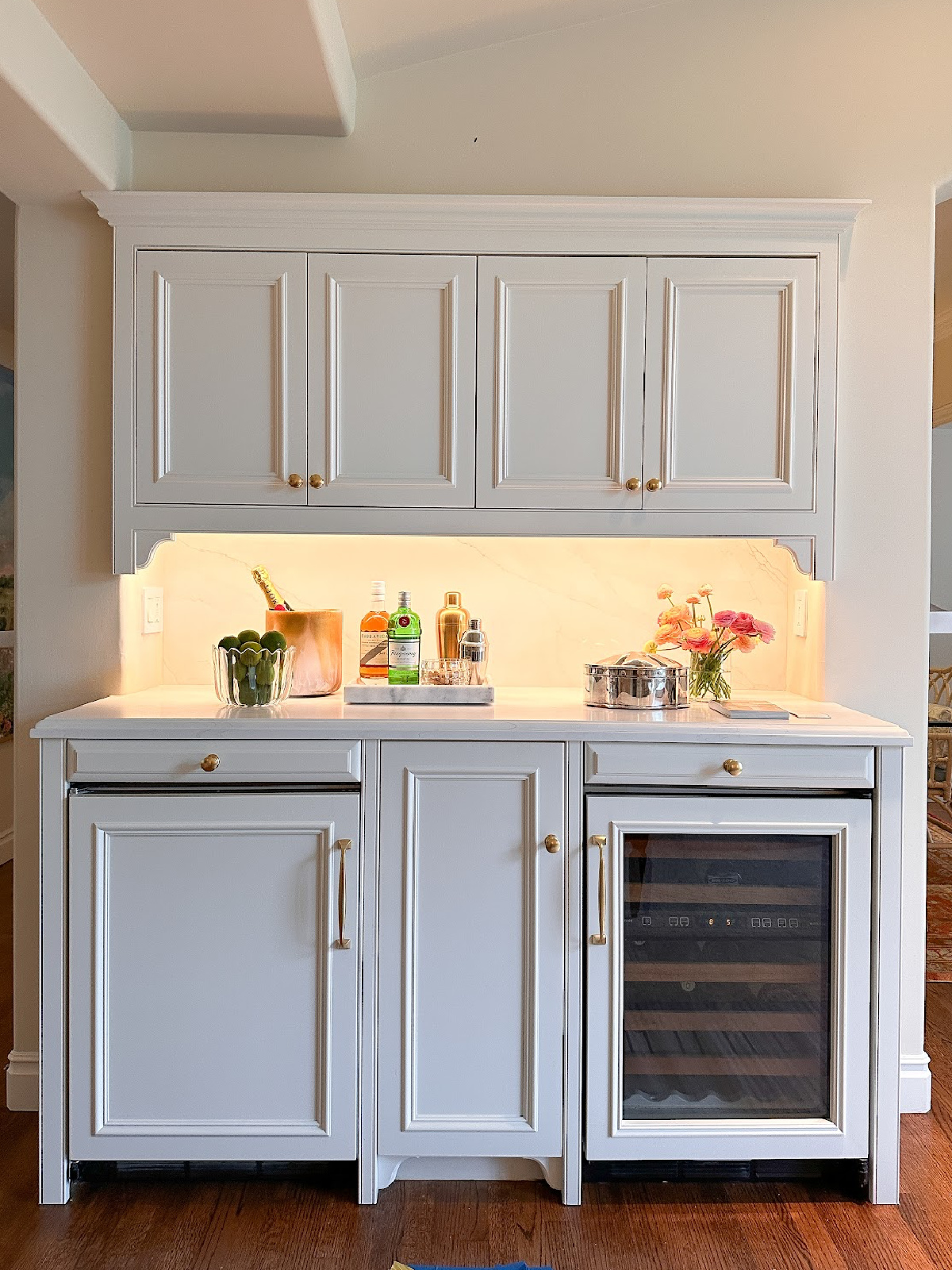 Built in bar area with white cabinetry and wine refrigerator.