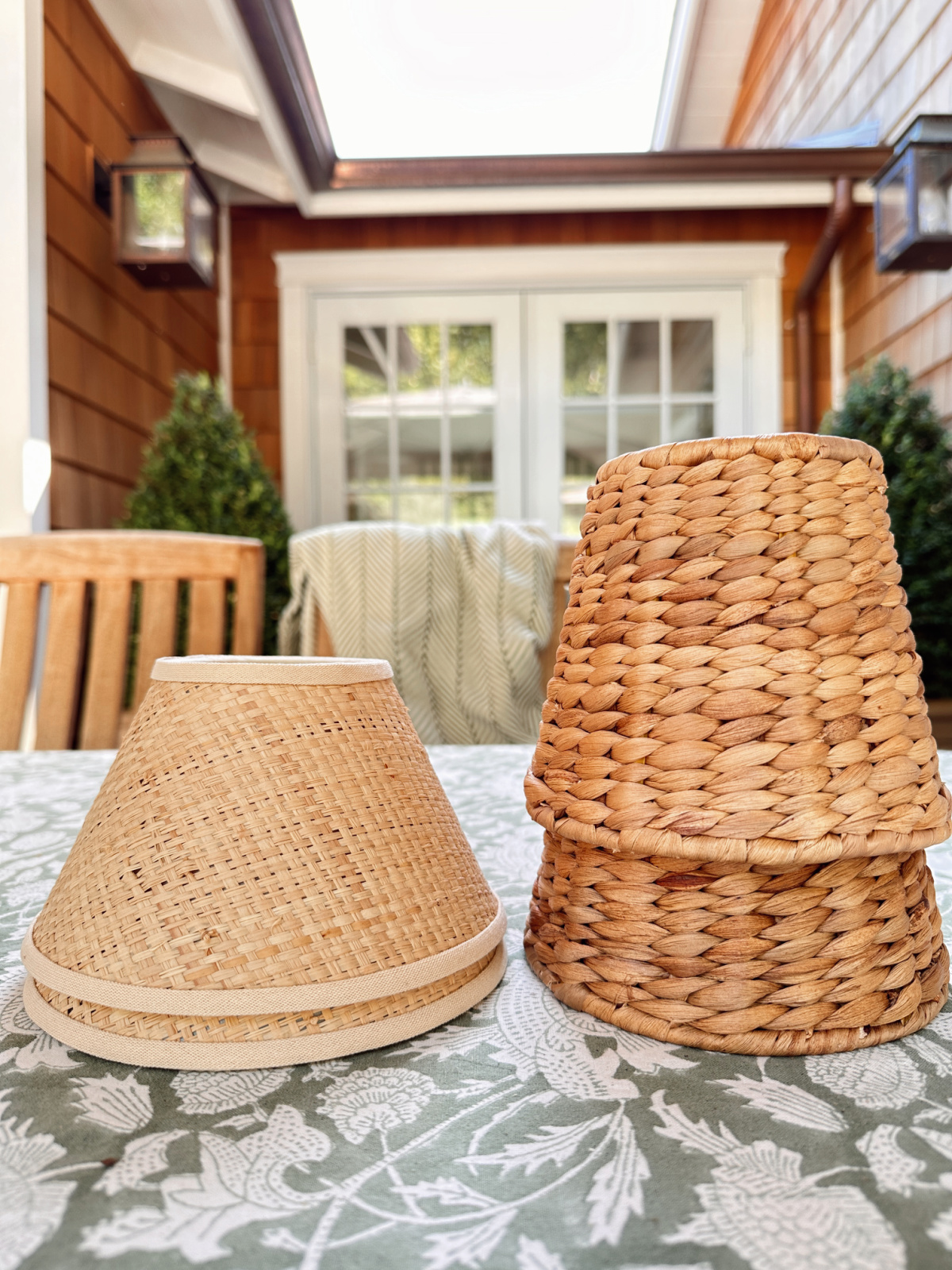 Two sets of cordless lamp shades stacked on top of one another on outdoor table.