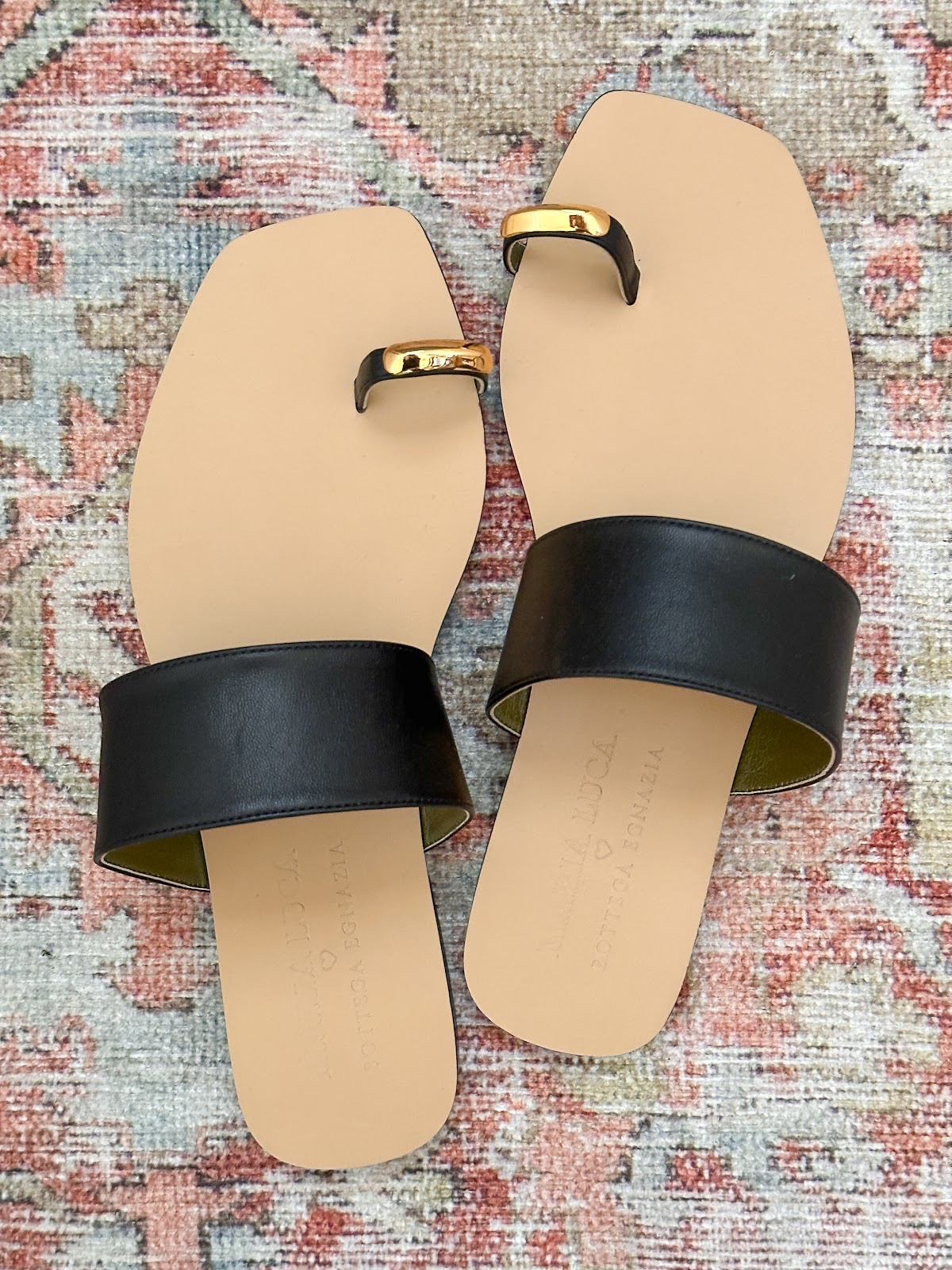 Overhead shot of metal toe ring sandals on a Persian style rug.