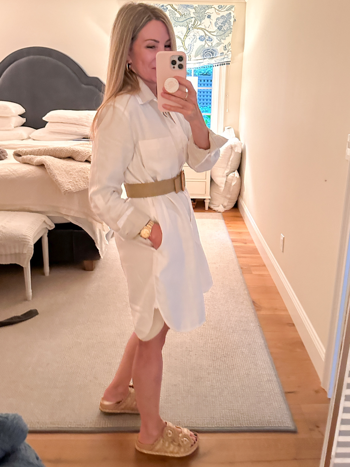 Woman wearing belted shirt dress taking mirror selfie.