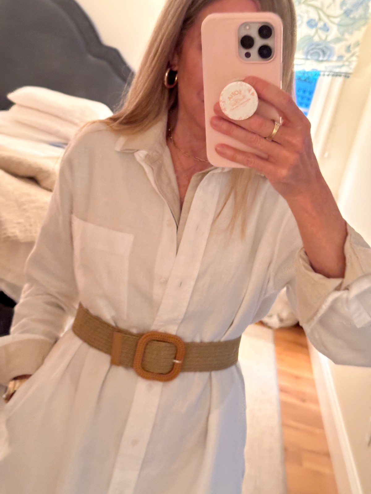 Woman wearing belted shirt dress taking mirror selfie.