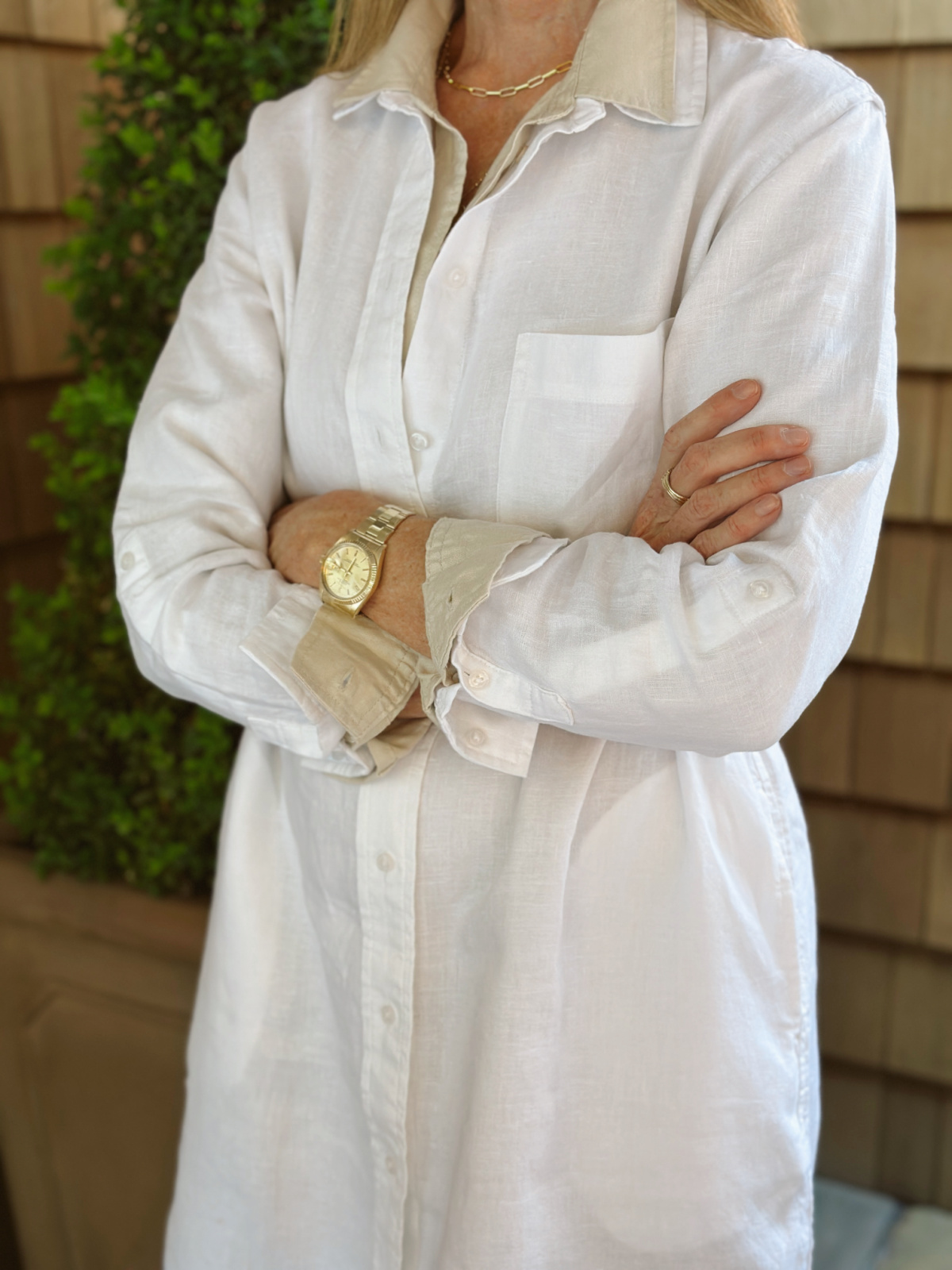 Woman wearing layered shirt dresses with arms crossed.