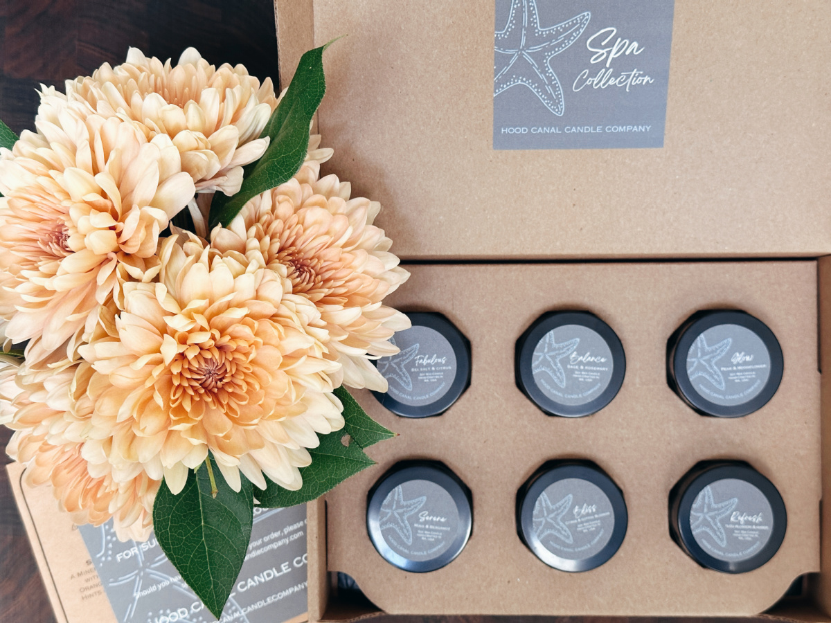 Box of spa scented sandals from Hood Canal Candle Co. next to a vase of peach flowers.