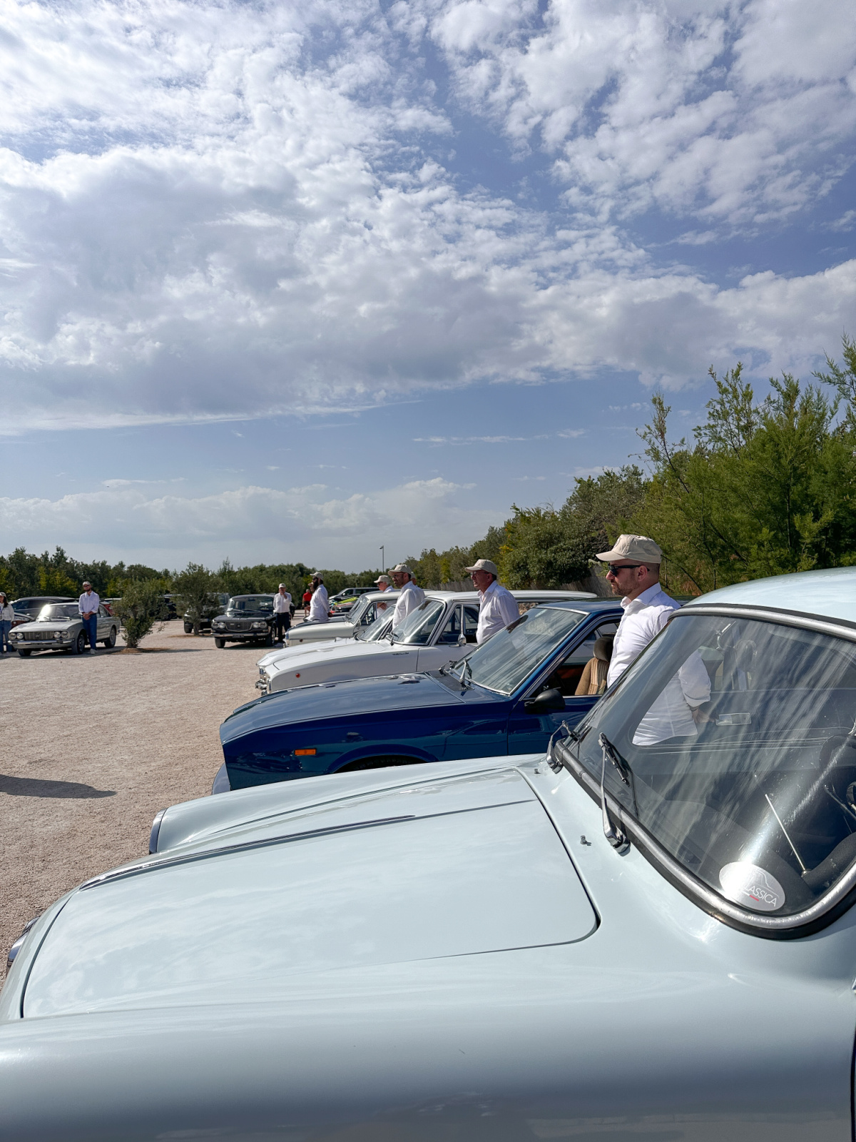 Vintage Italian cars in parking lot.