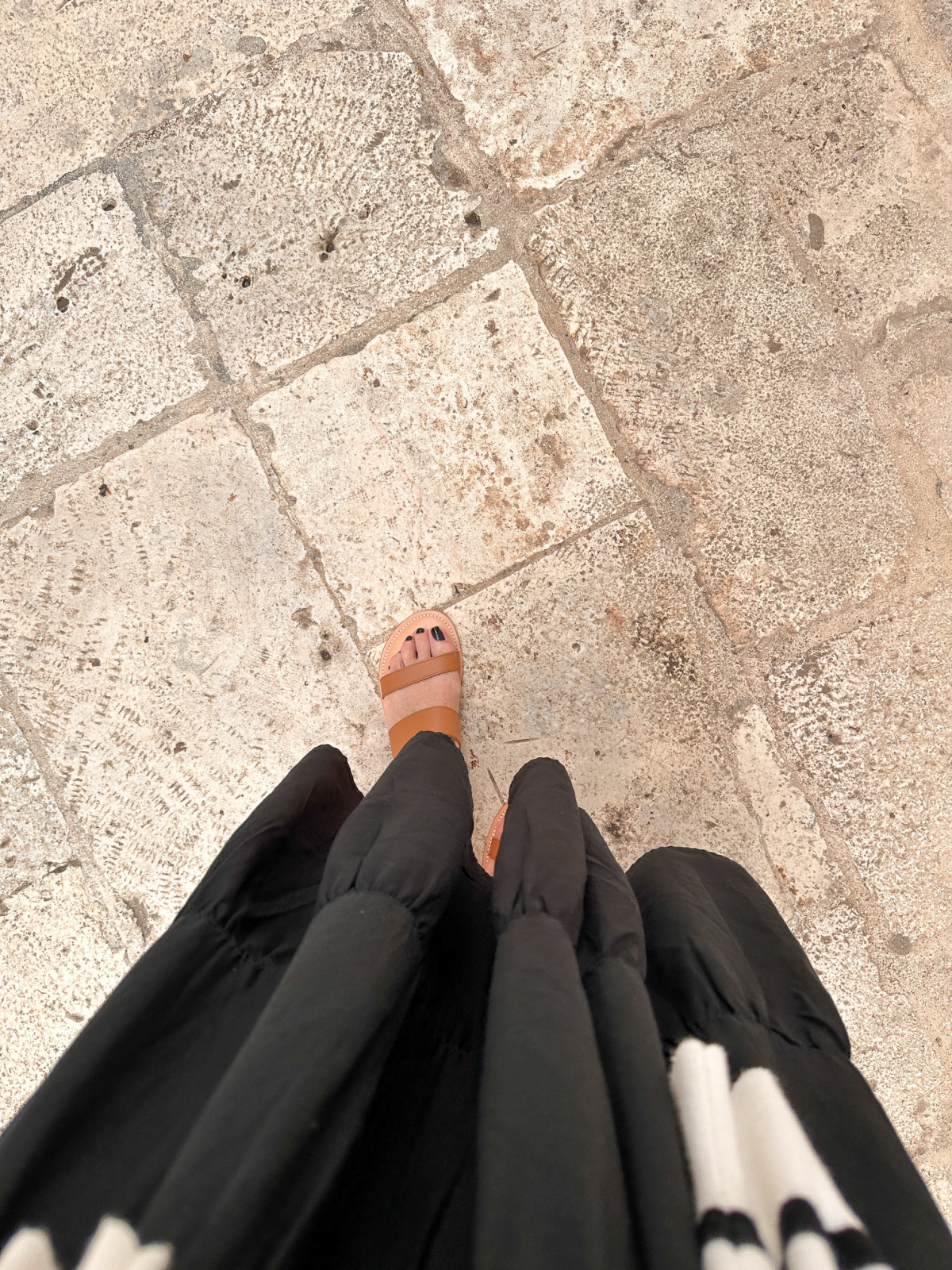 Overhead shot of women wearing sandals on stone streets of Italy.