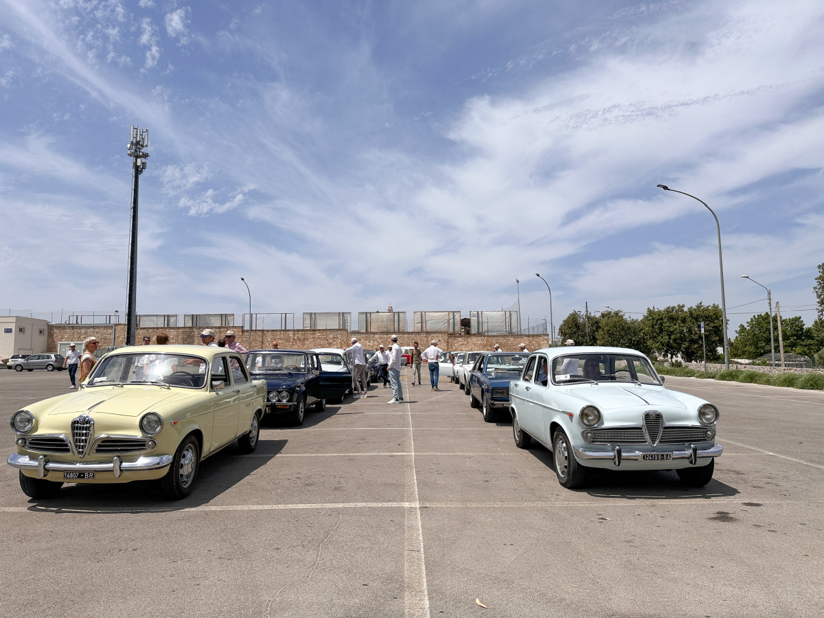 Vintage Italian cars lined up in parking lot.