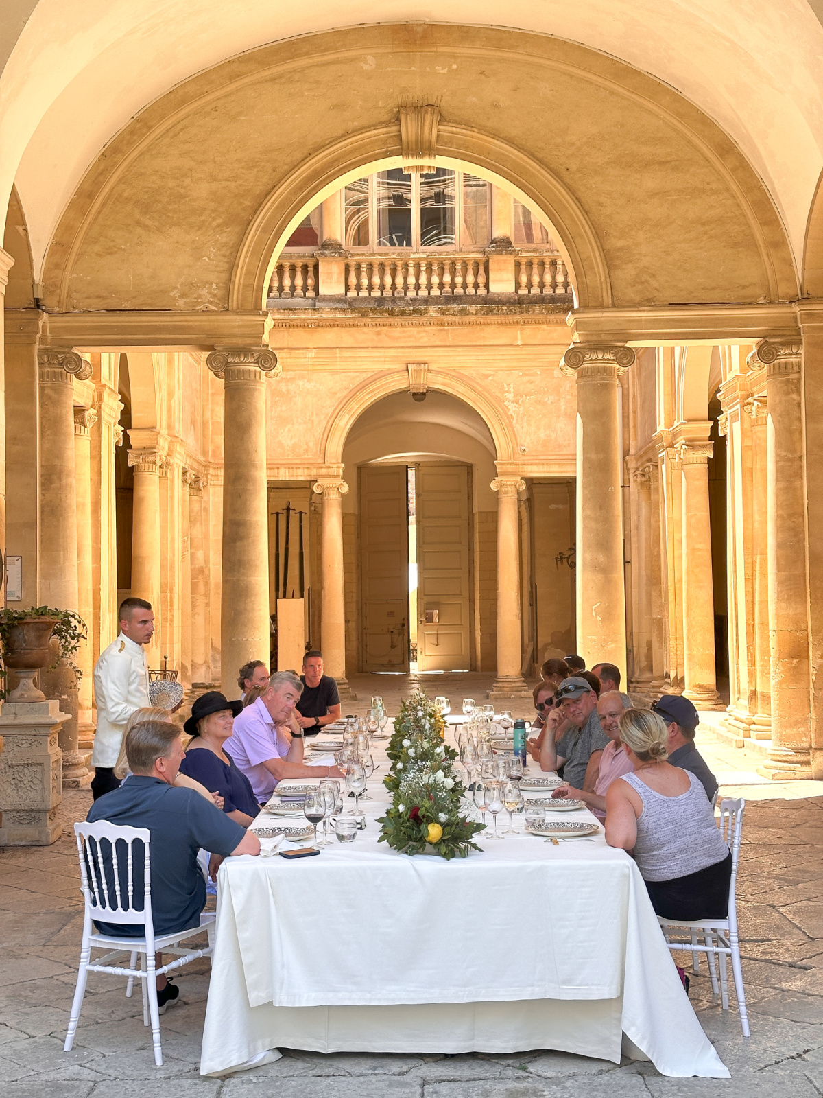 Large table of people seated in palazzo courtyard.