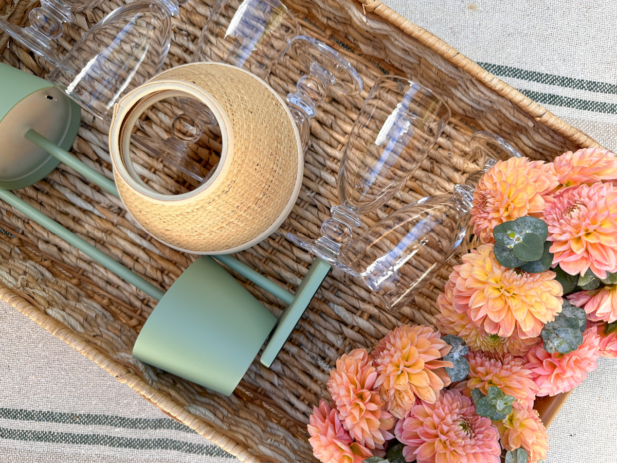 Woven tray holding table lamps, wine glasses and flower arrangements.